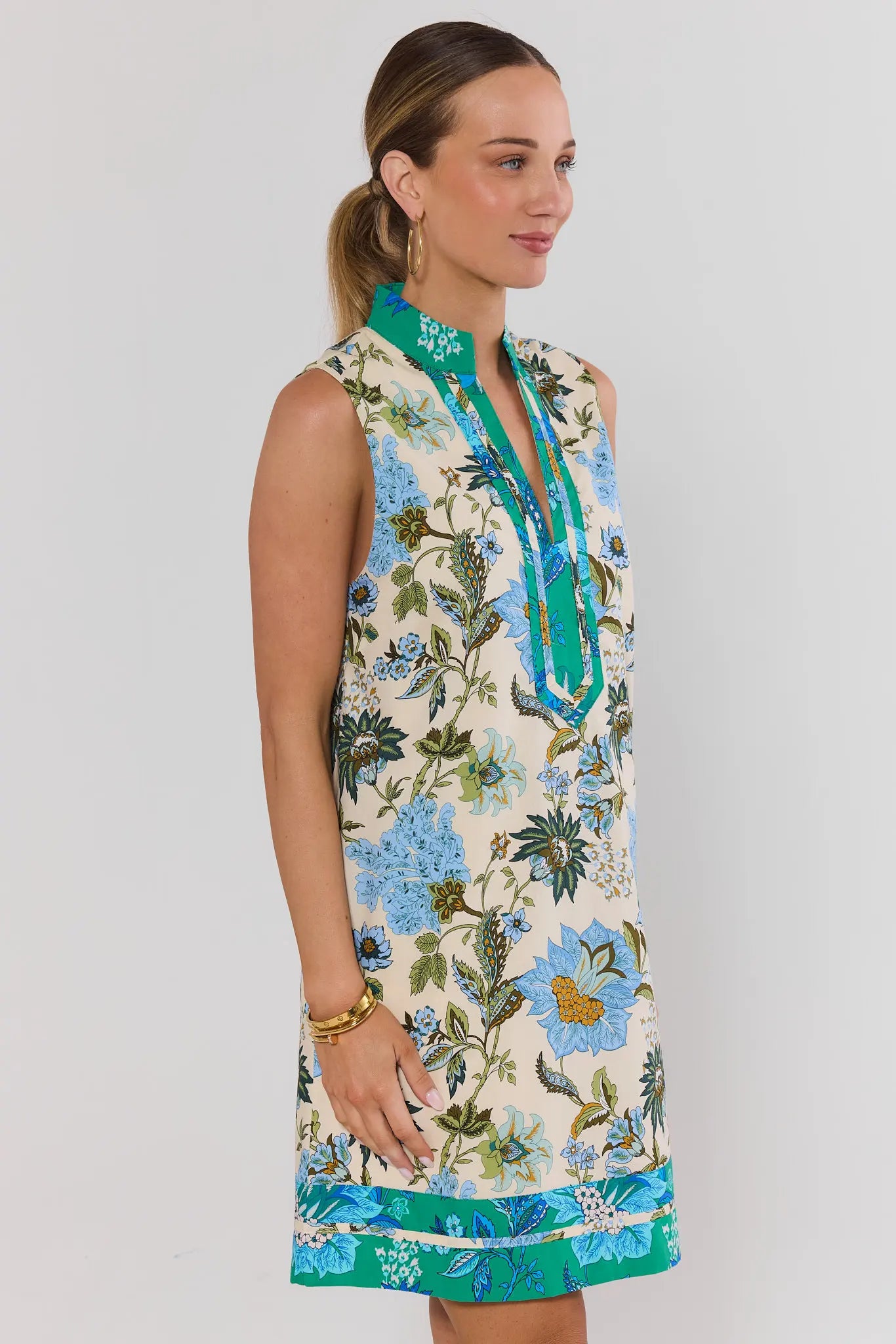 side shot Woman wearing a sleeveless floral dress with a white background