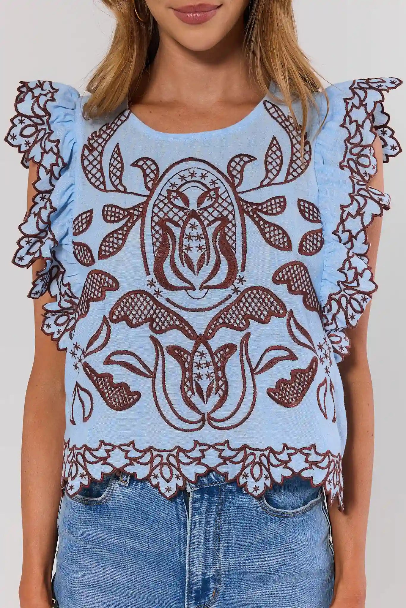 close up Light blue top with brown floral patterns and ruffled sleeves worn by a person.