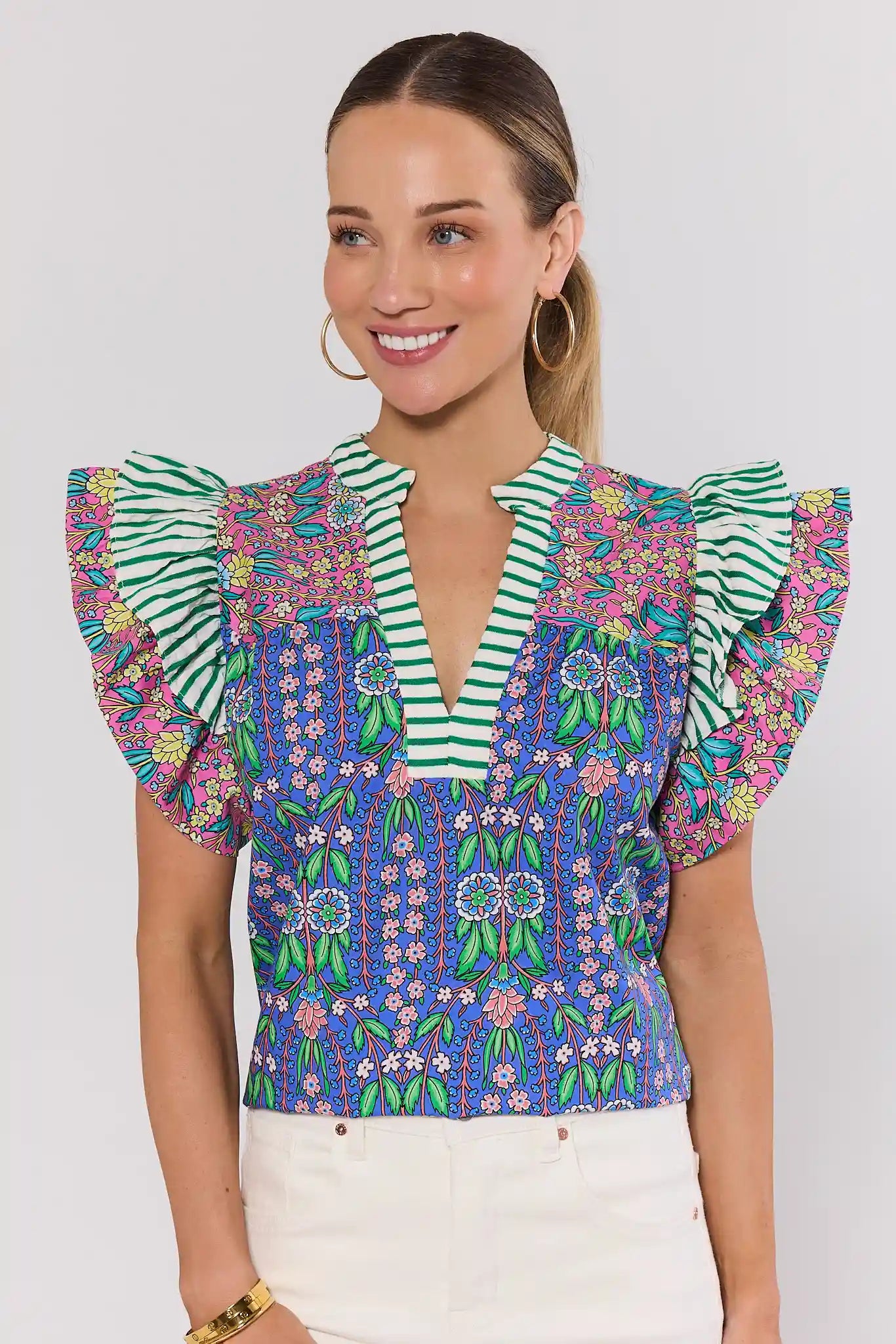 Woman wearing a colorful floral blouse with ruffled sleeves on a white background