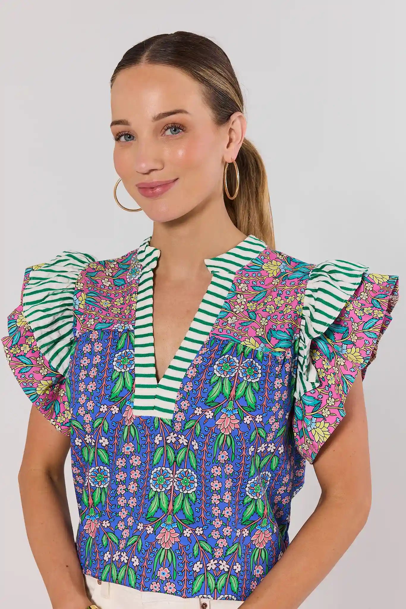 Woman wearing a colorful patterned blouse with ruffled sleeves on a white background close up 