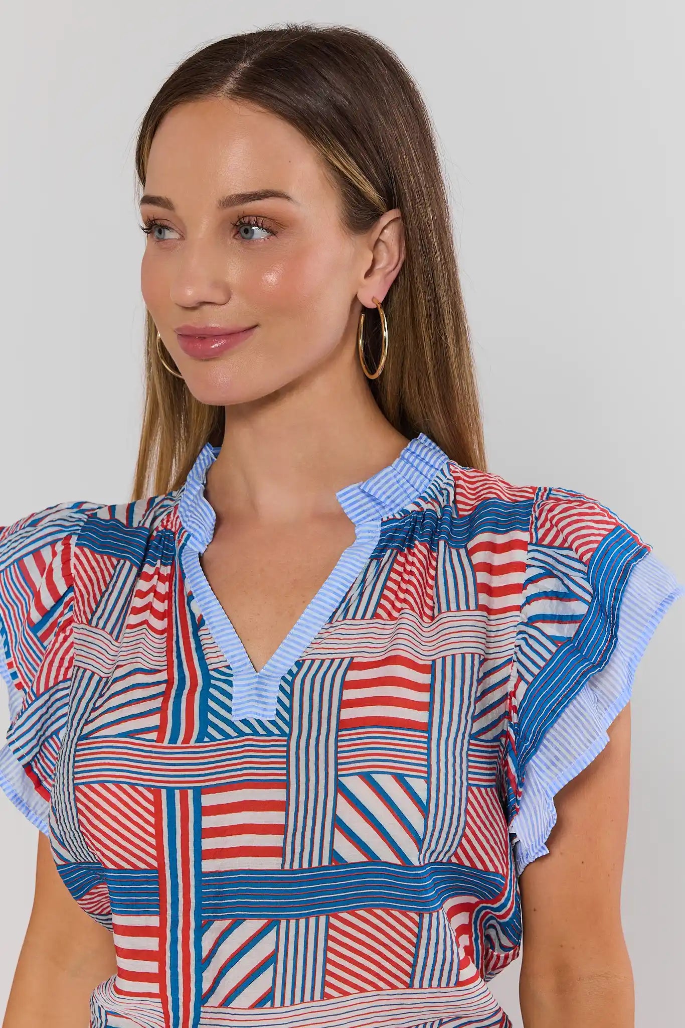 Woman wearing a colorful patterned top against a plain background close up