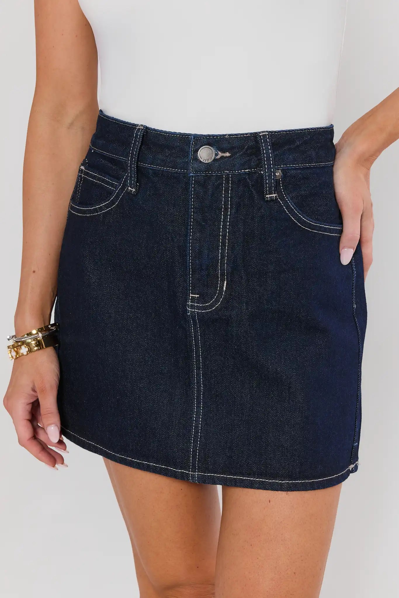 Denim skirt worn by a person on a plain background