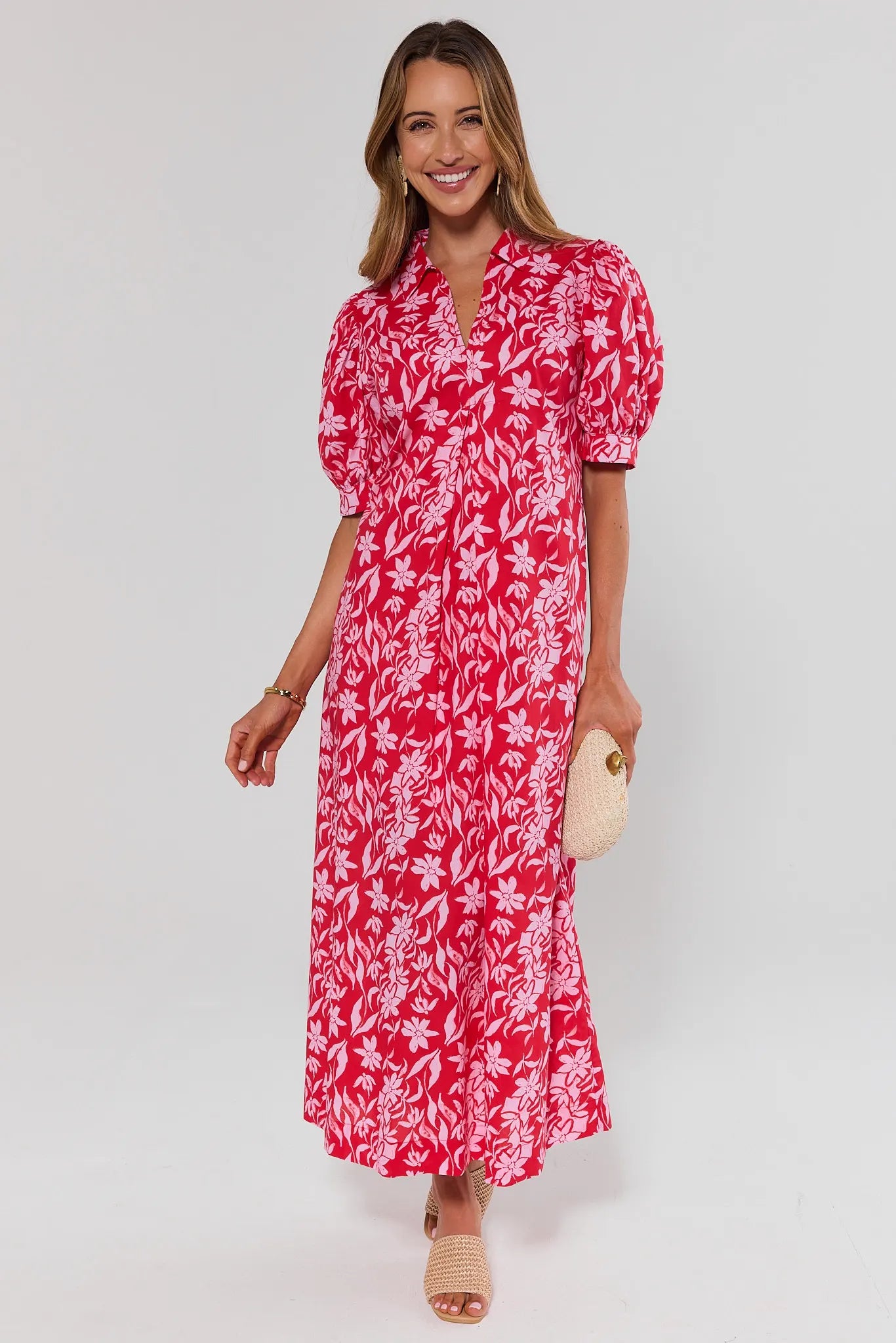Woman wearing a red floral dress on a white background standing