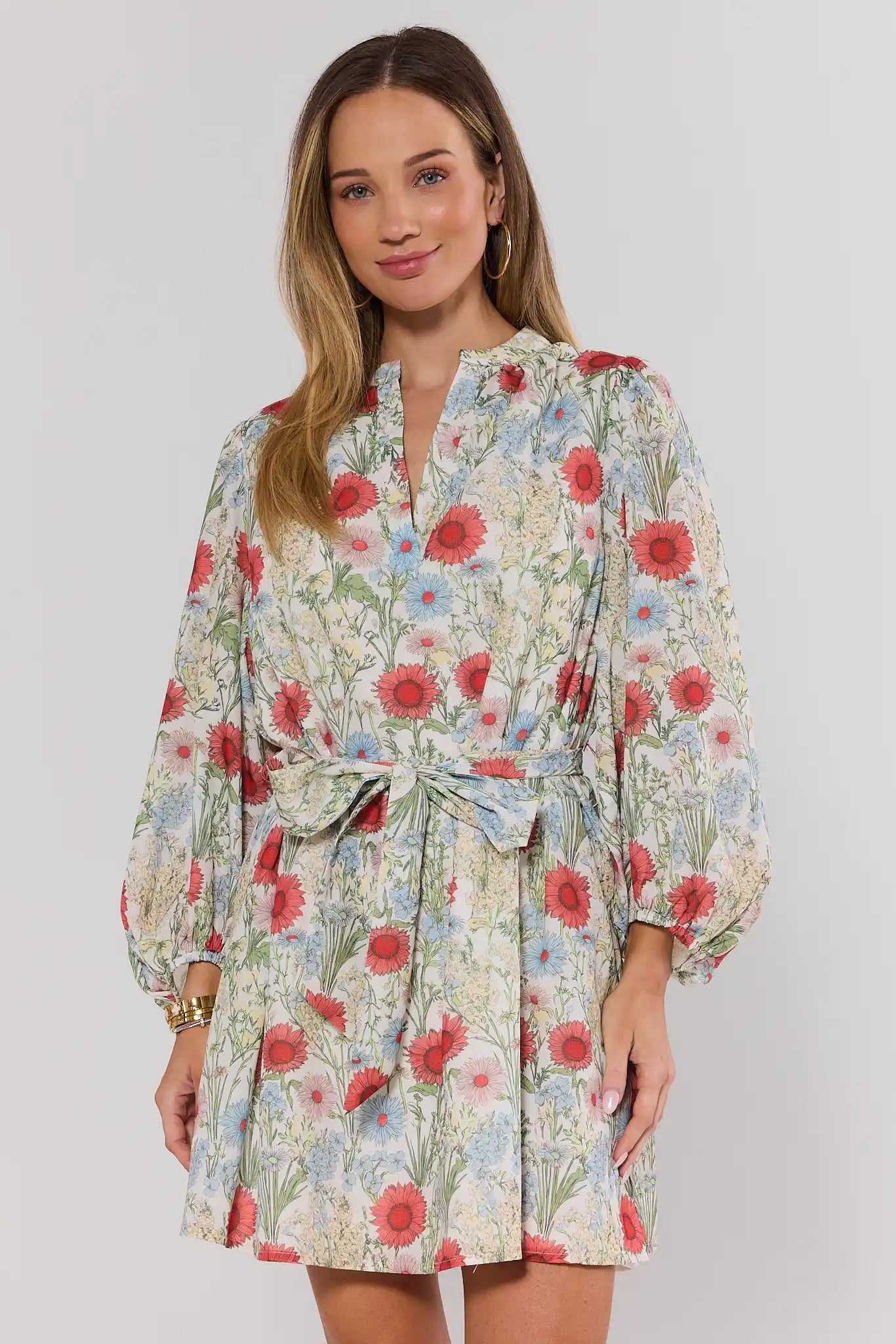 Woman wearing a floral dress with long sleeves on a plain background