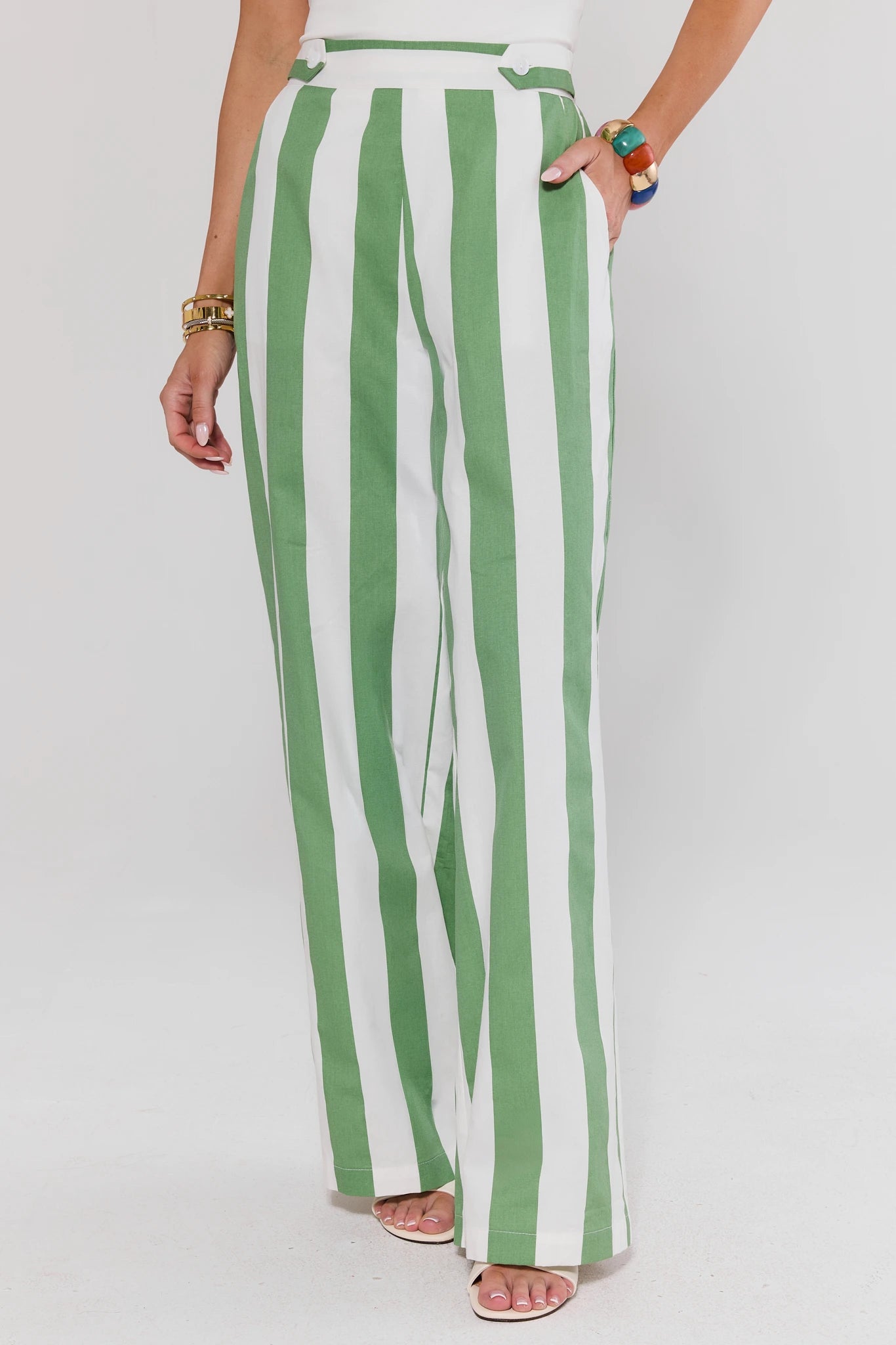 Green and white striped pants worn by a person on a plain background