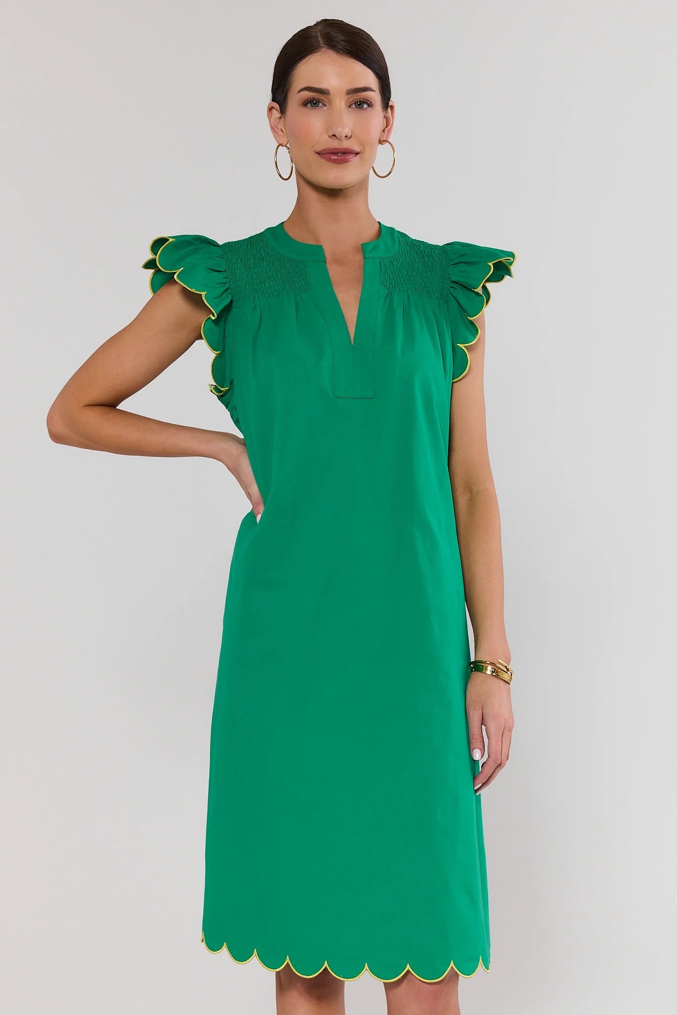 Woman wearing a green dress with scalloped edges on a white background