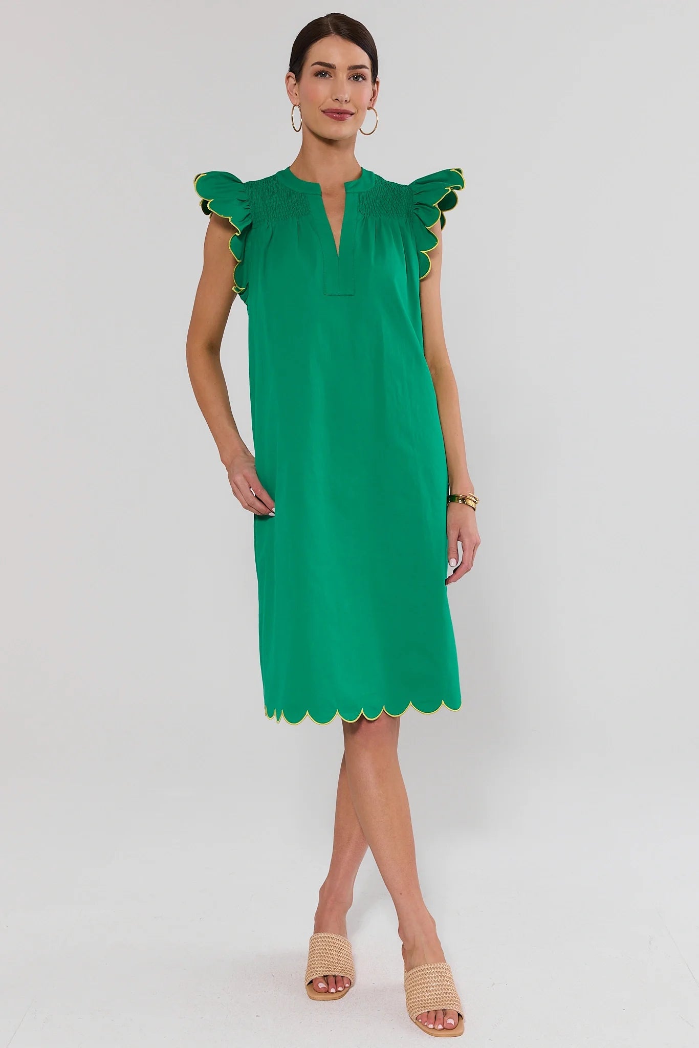 Woman wearing a green dress with ruffled sleeves on a white background stand
