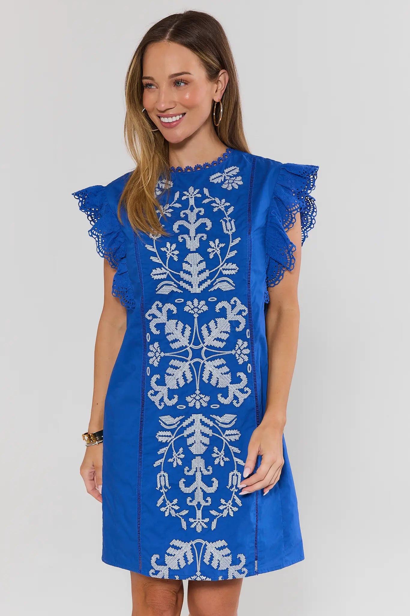 Woman wearing a blue dress with white floral embroidery on a white background