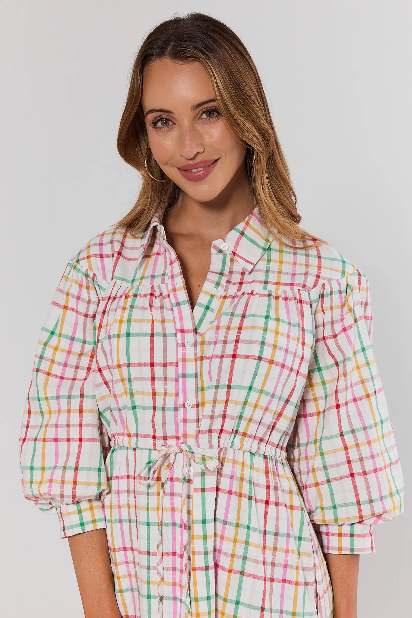 Woman wearing a colorful plaid dress against a plain background close up