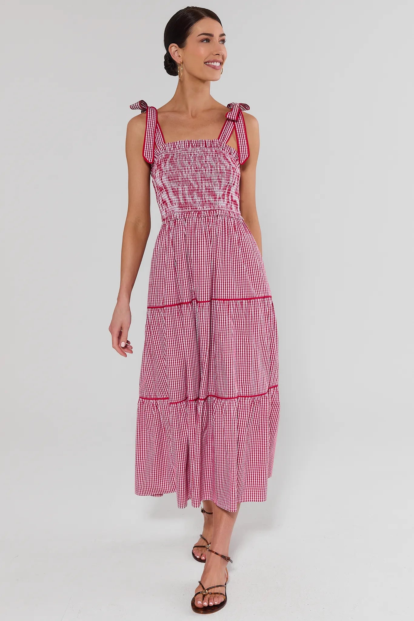 Woman wearing a red and gingham dress on a white background