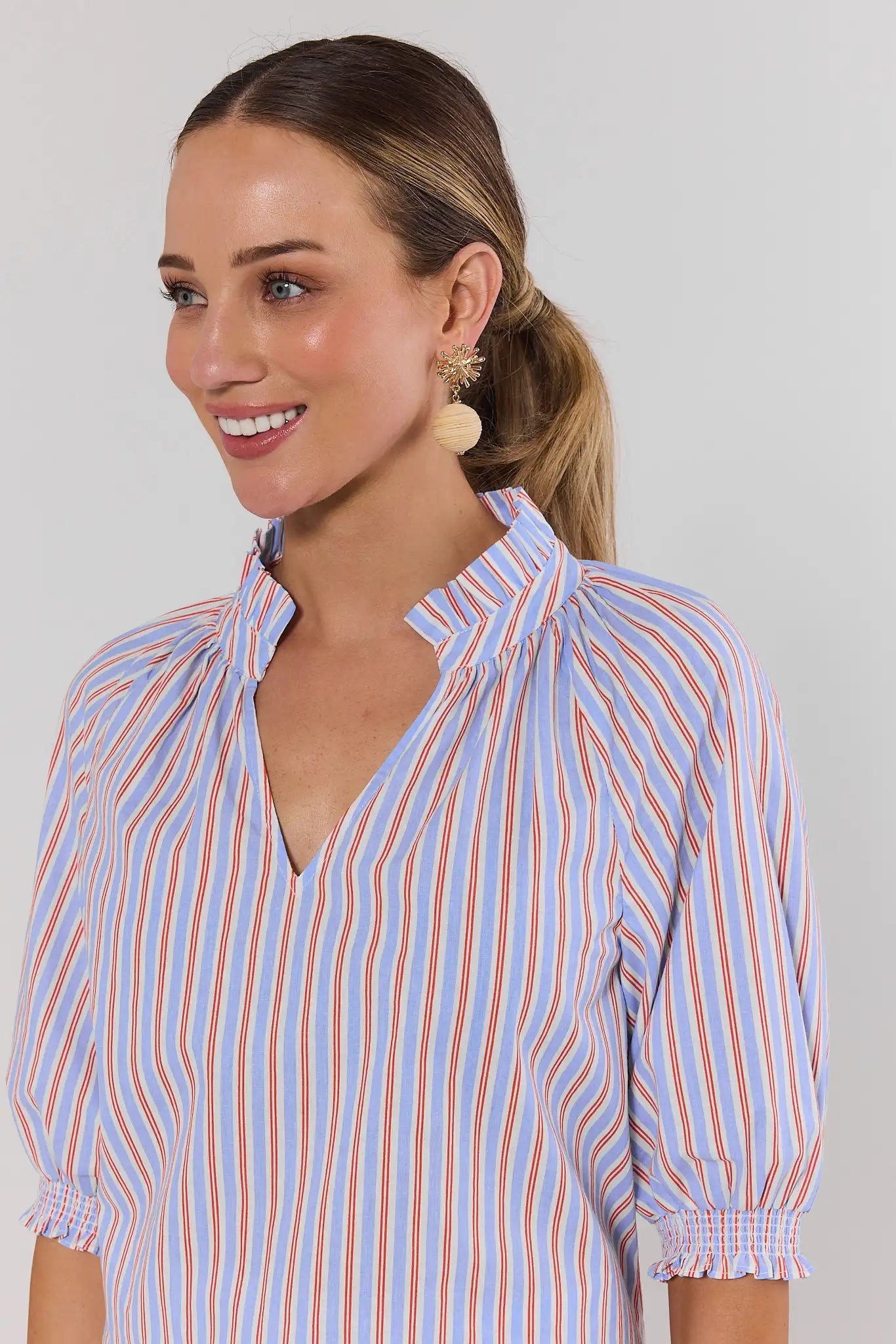 close up Woman wearing a blue and orange striped shirt against a plain background