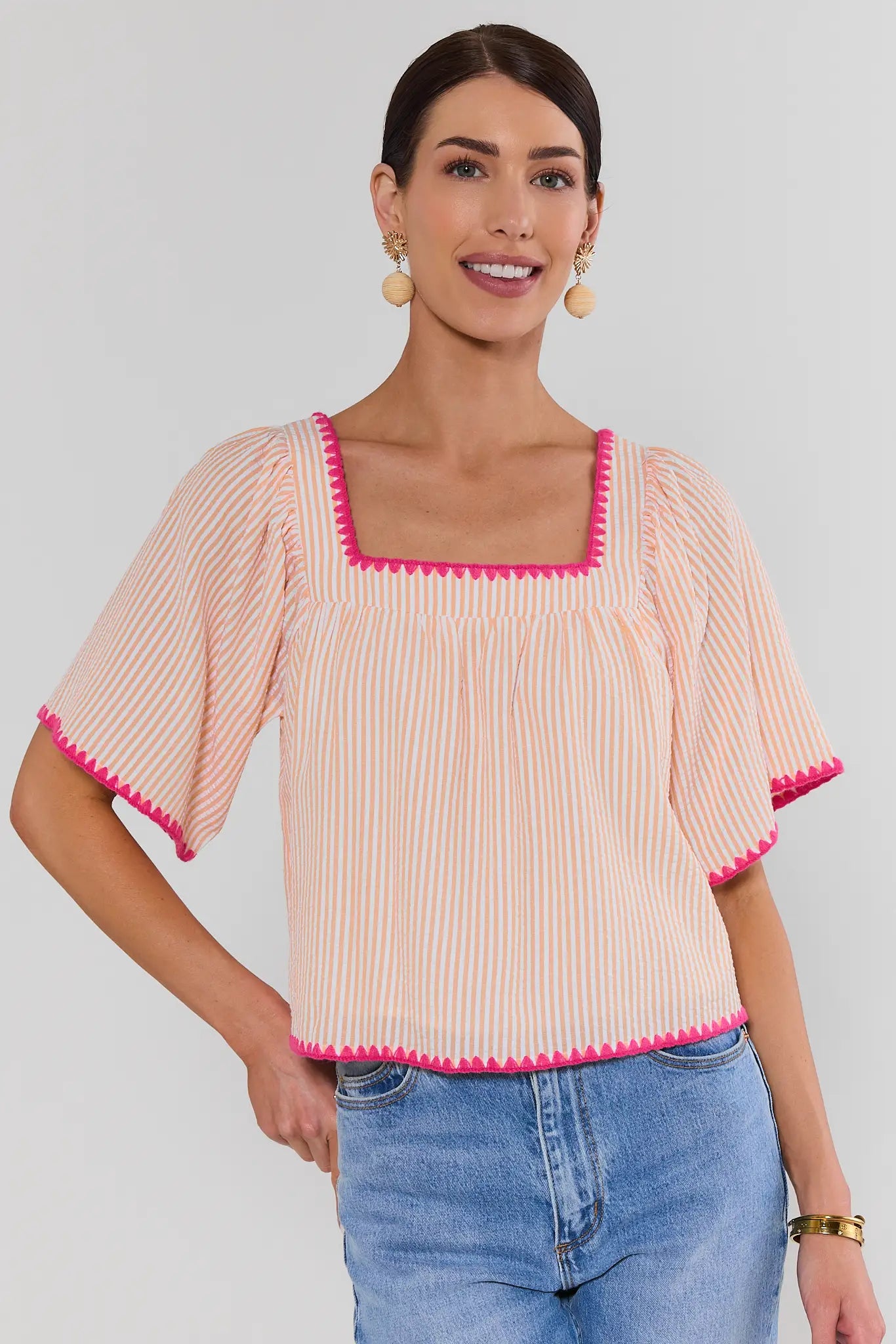 Woman wearing a pink and white striped top with pink trim on a plain background