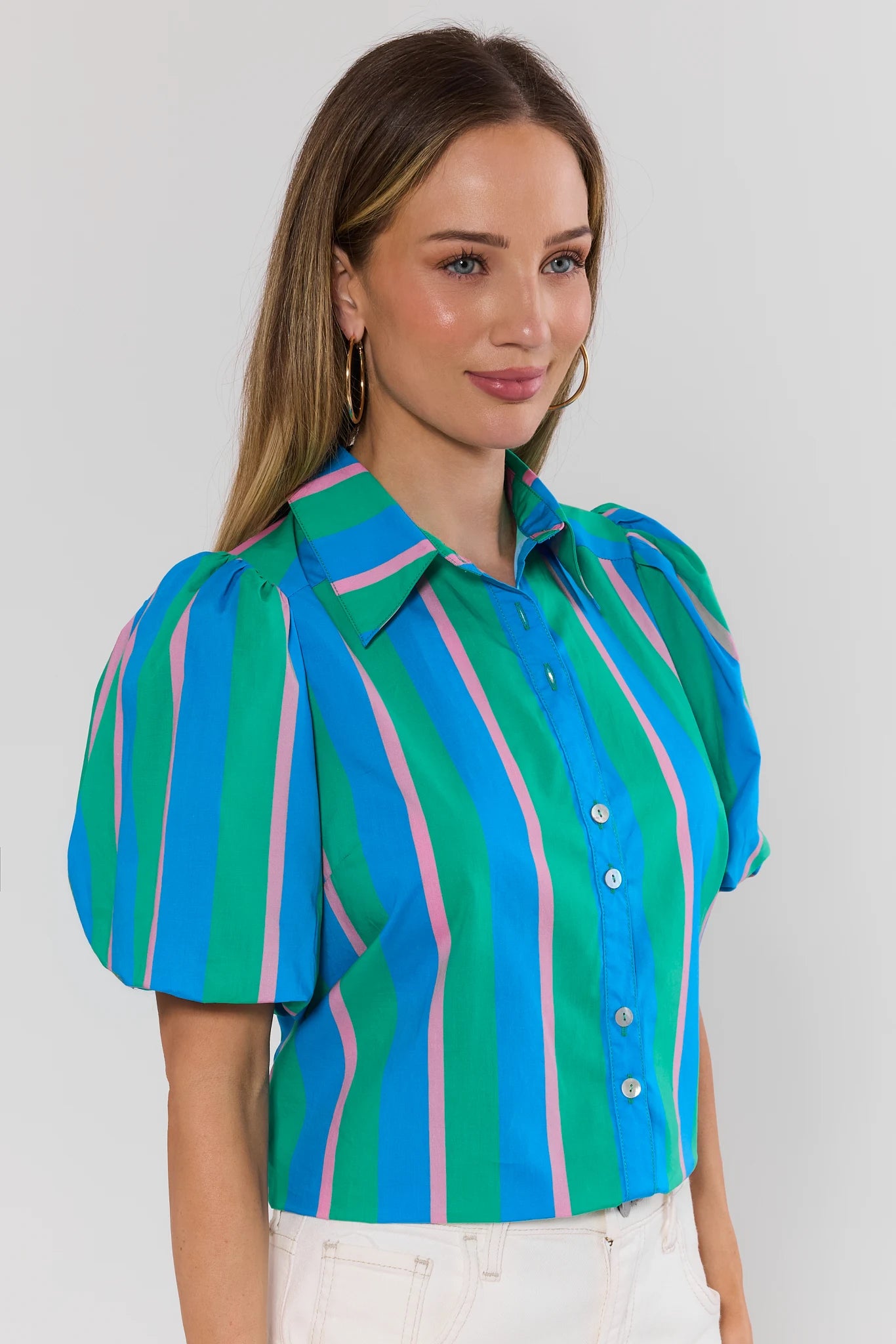 Woman wearing a colorful striped shirt against a plain background side
