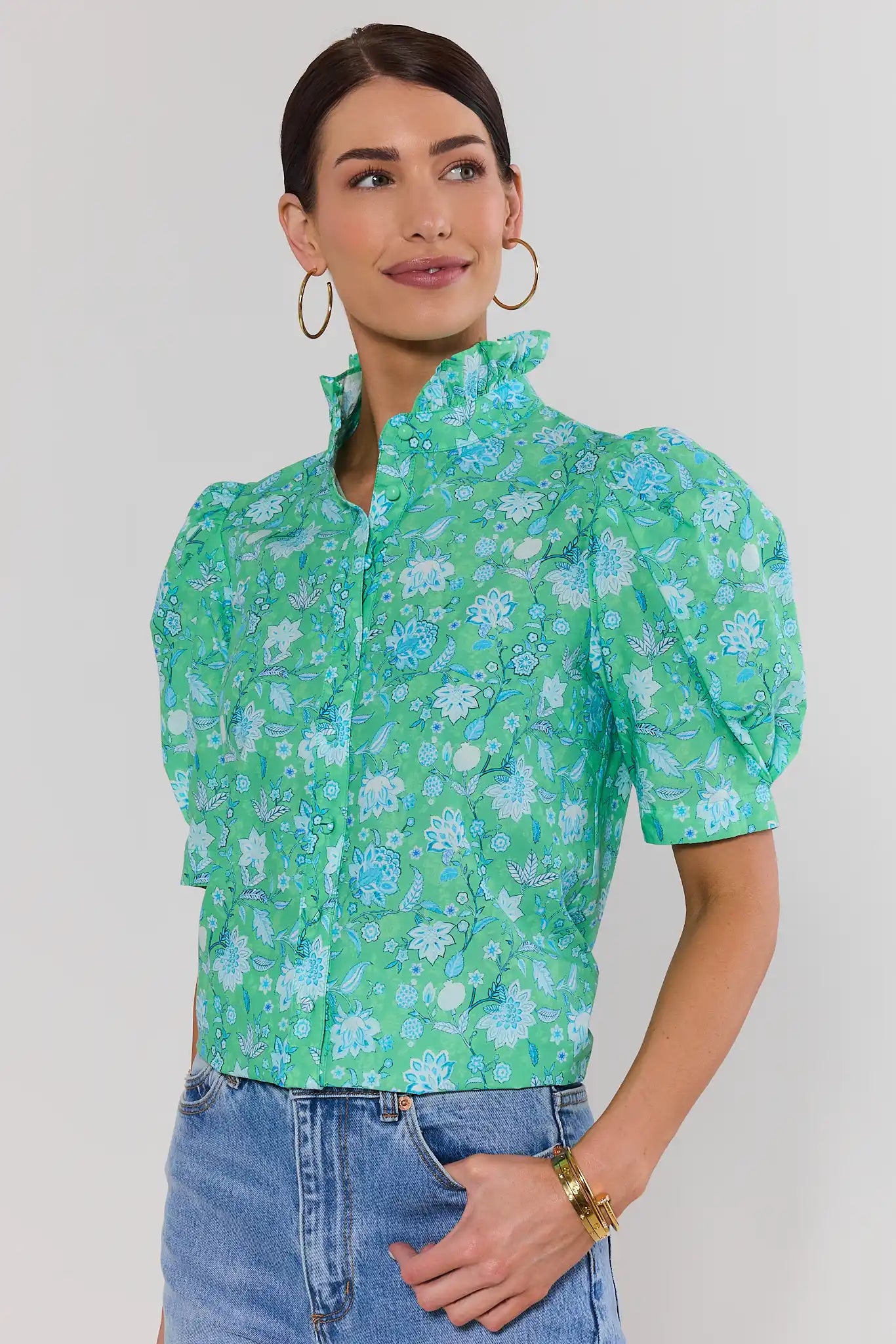 Woman wearing a green floral blouse against a plain background