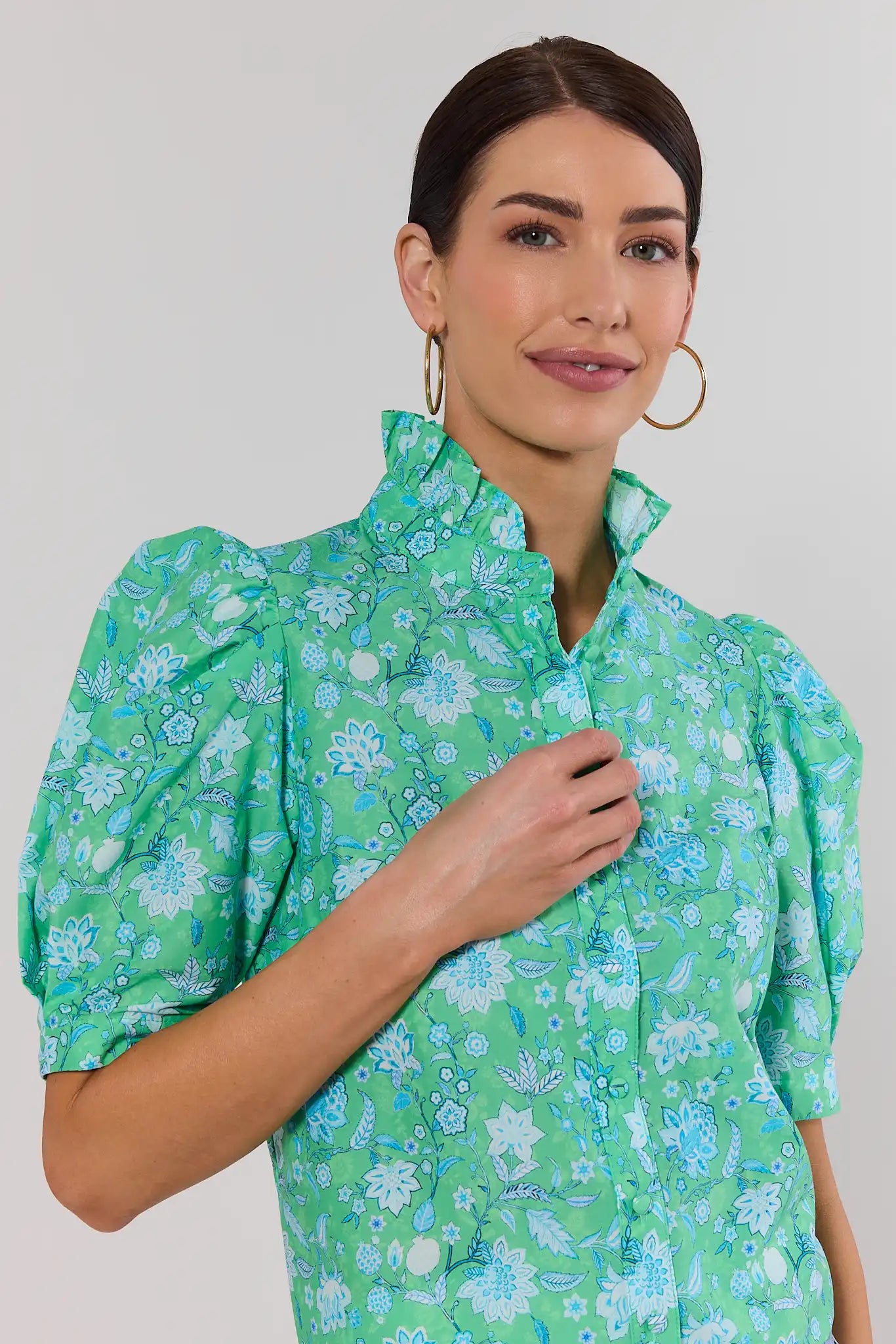 close up Woman wearing a green floral blouse against a plain background