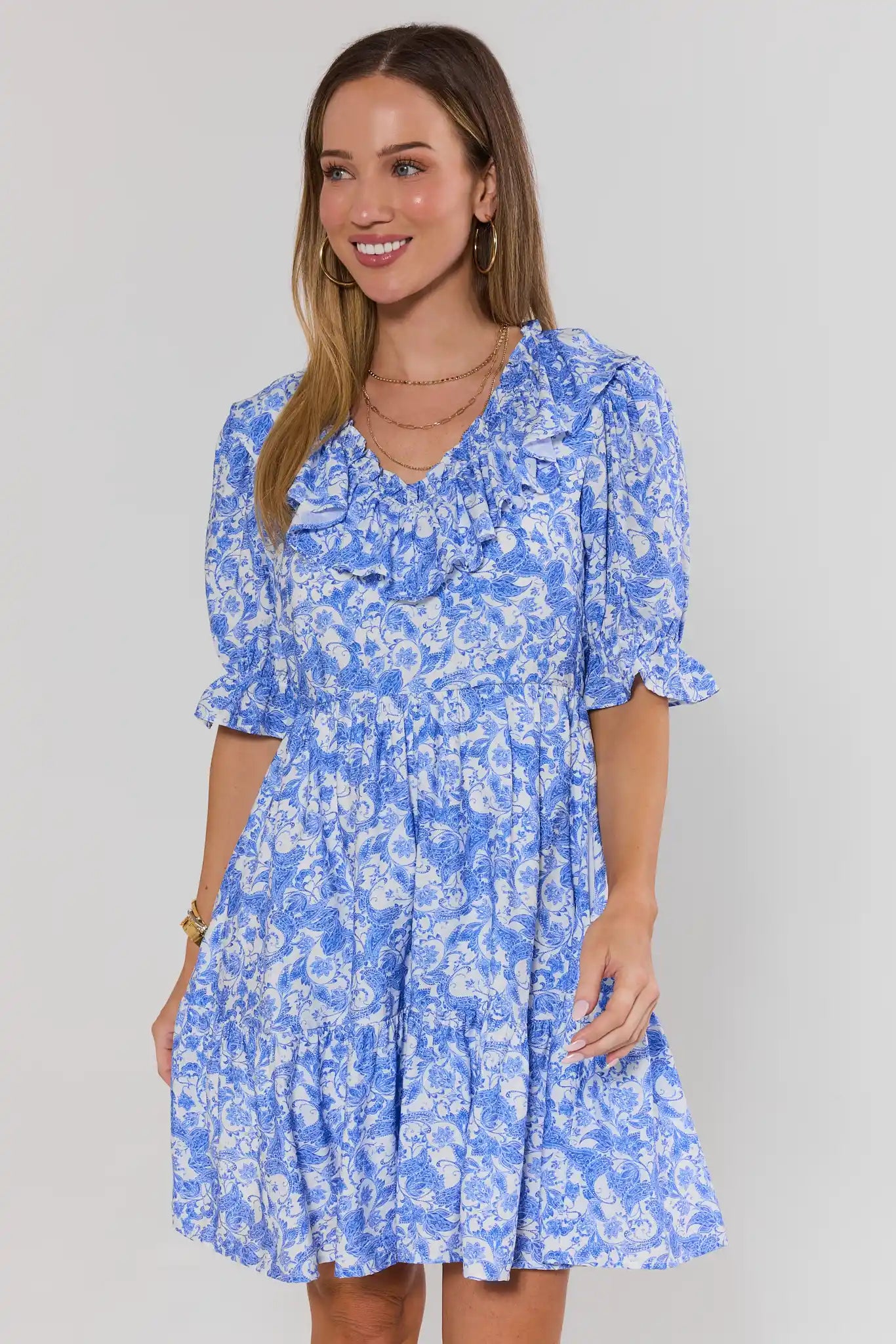 Woman wearing a blue floral dress against a plain background