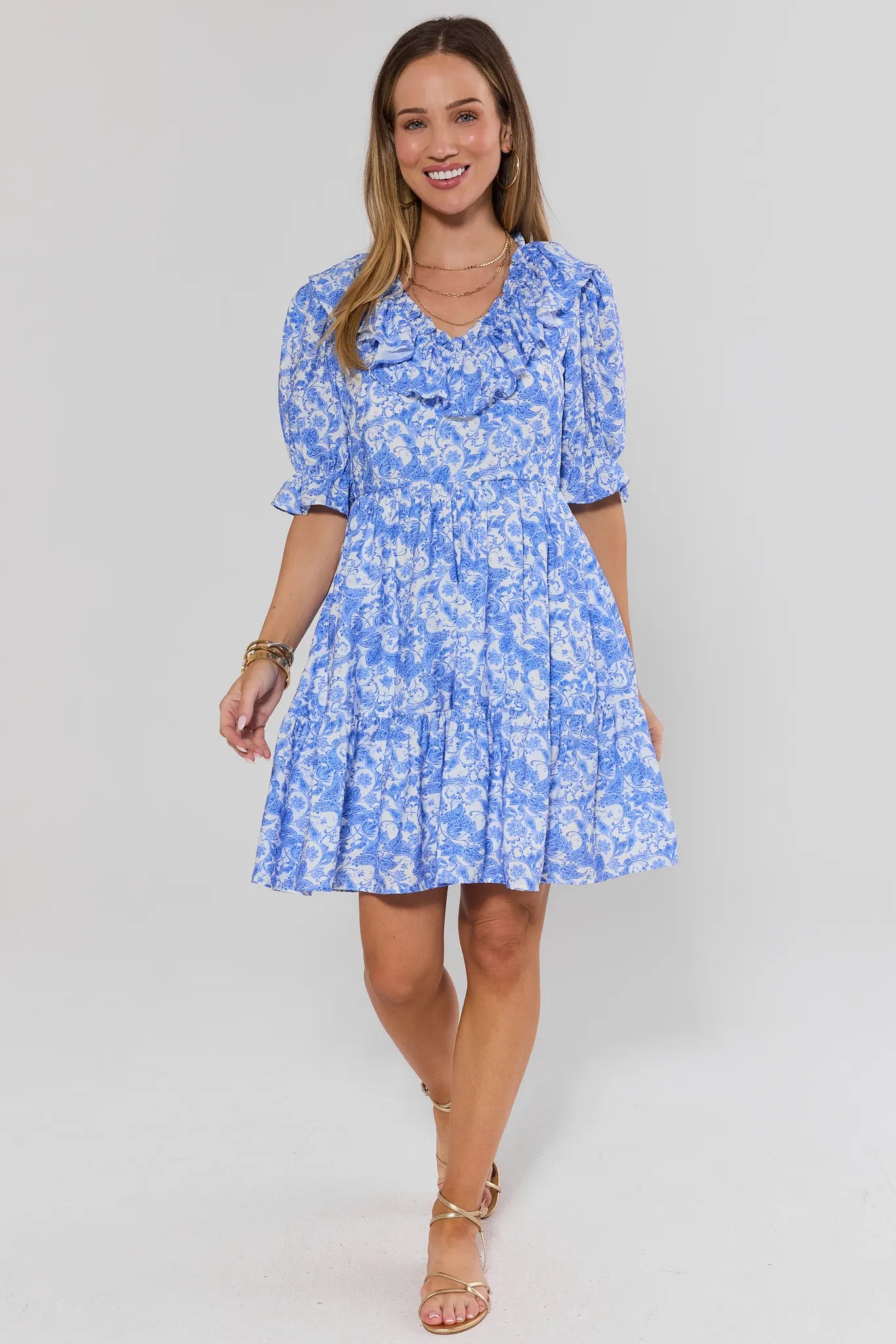 Woman wearing a blue ruffle floral dress on a white background