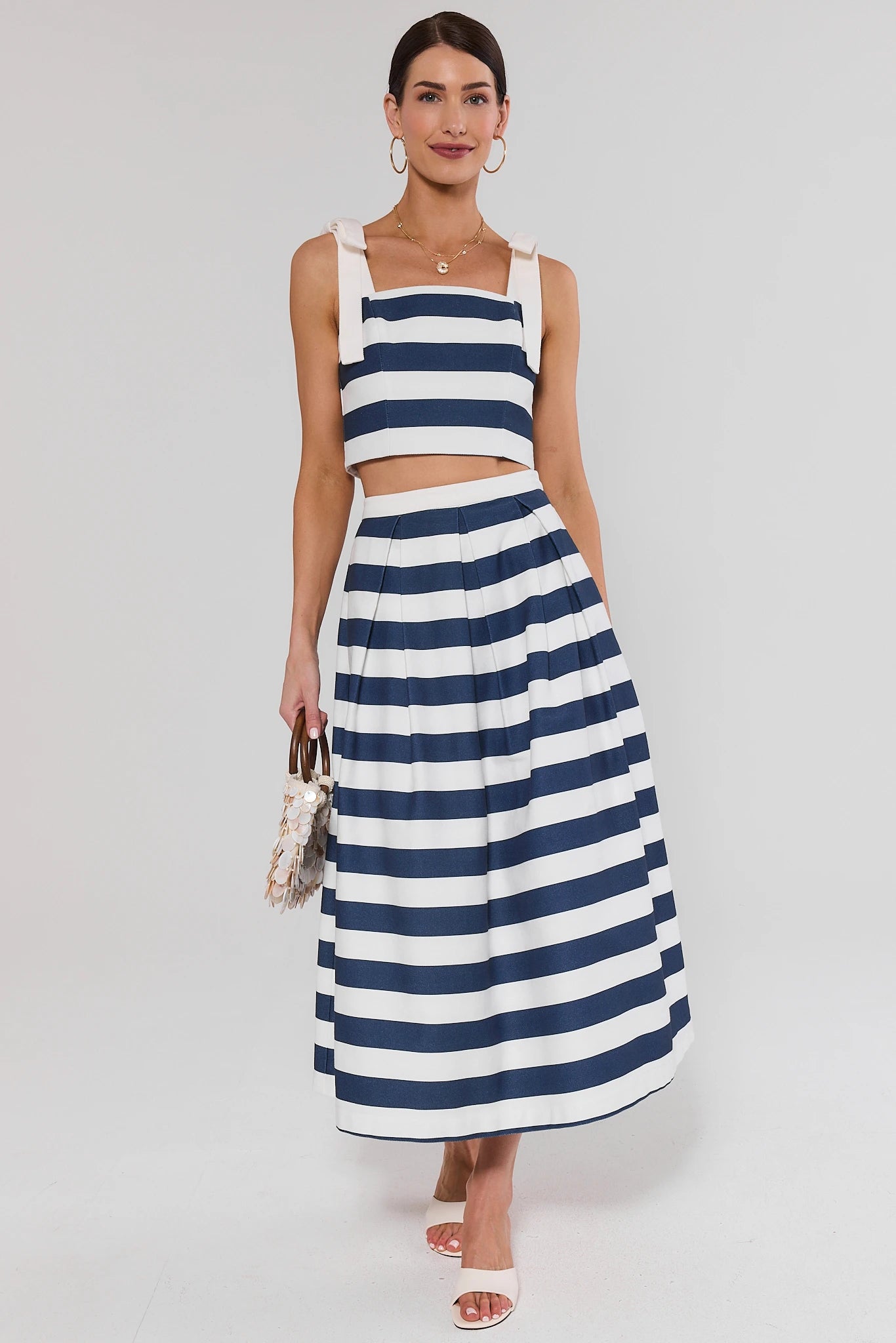 Woman wearing a blue and white striped top and skirt on a plain background