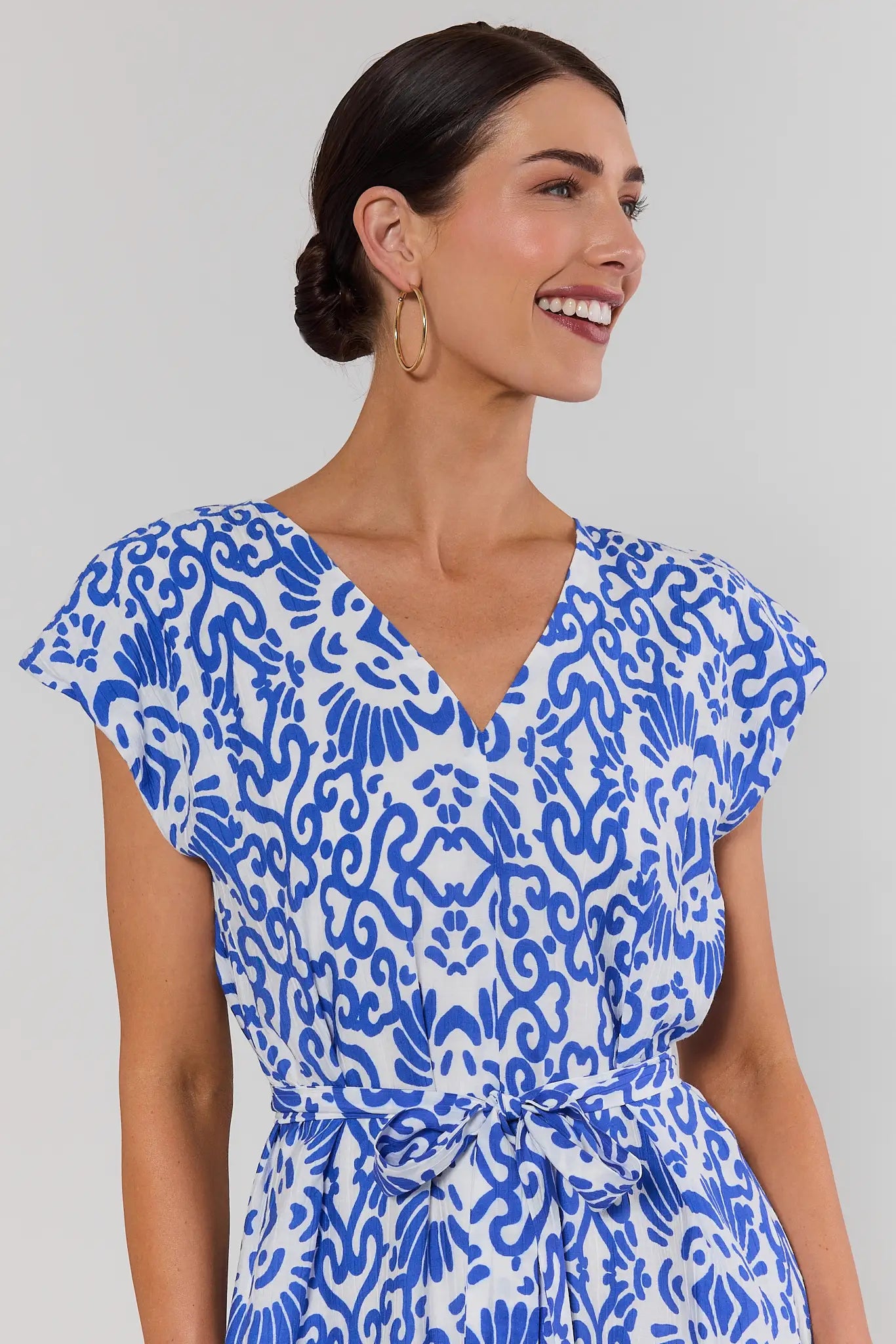 close up Woman wearing a blue and white patterned dress on a plain background