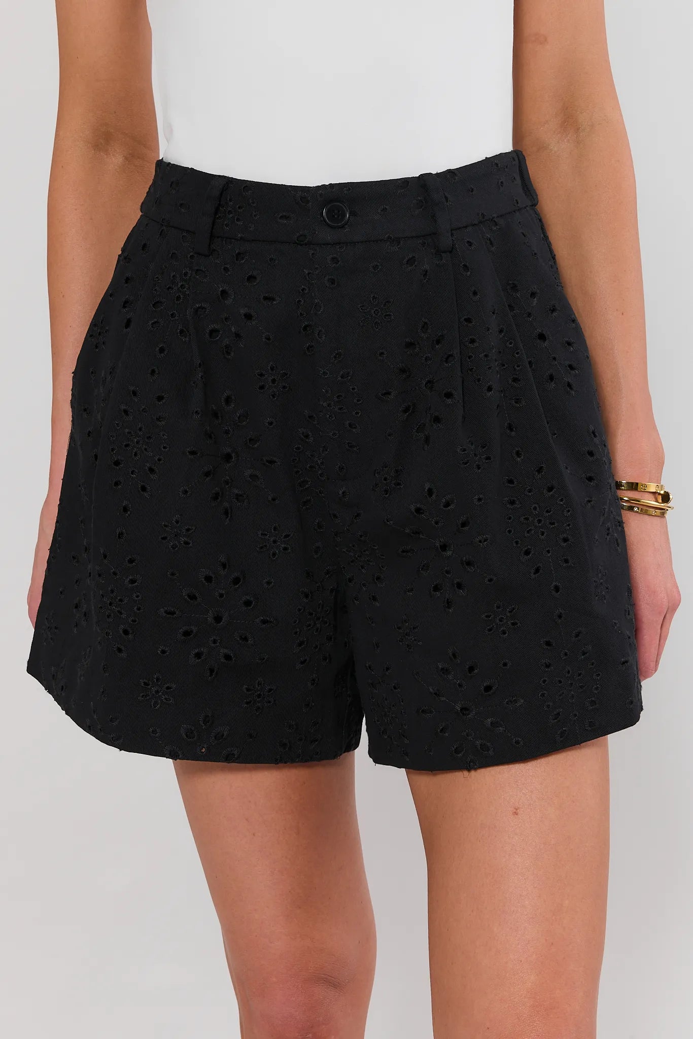 Black shorts with eyelet details worn by a person on a white background