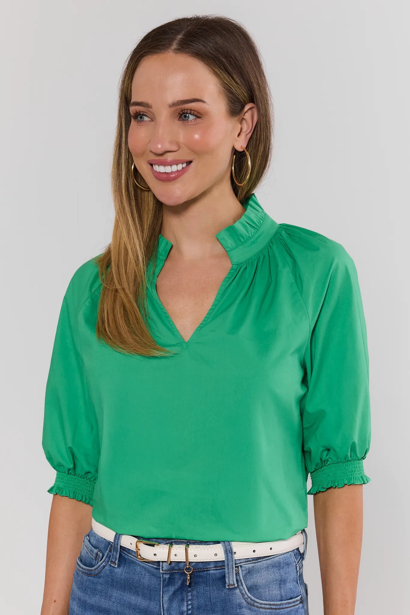 Woman wearing a green blouse with puffed sleeves against a plain background