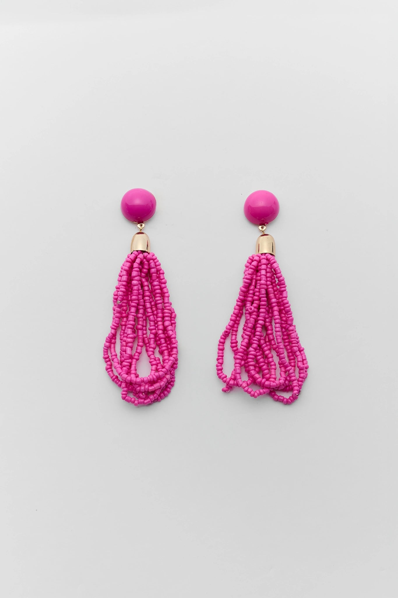 Pair of pink beaded tassel earrings on a light gray background