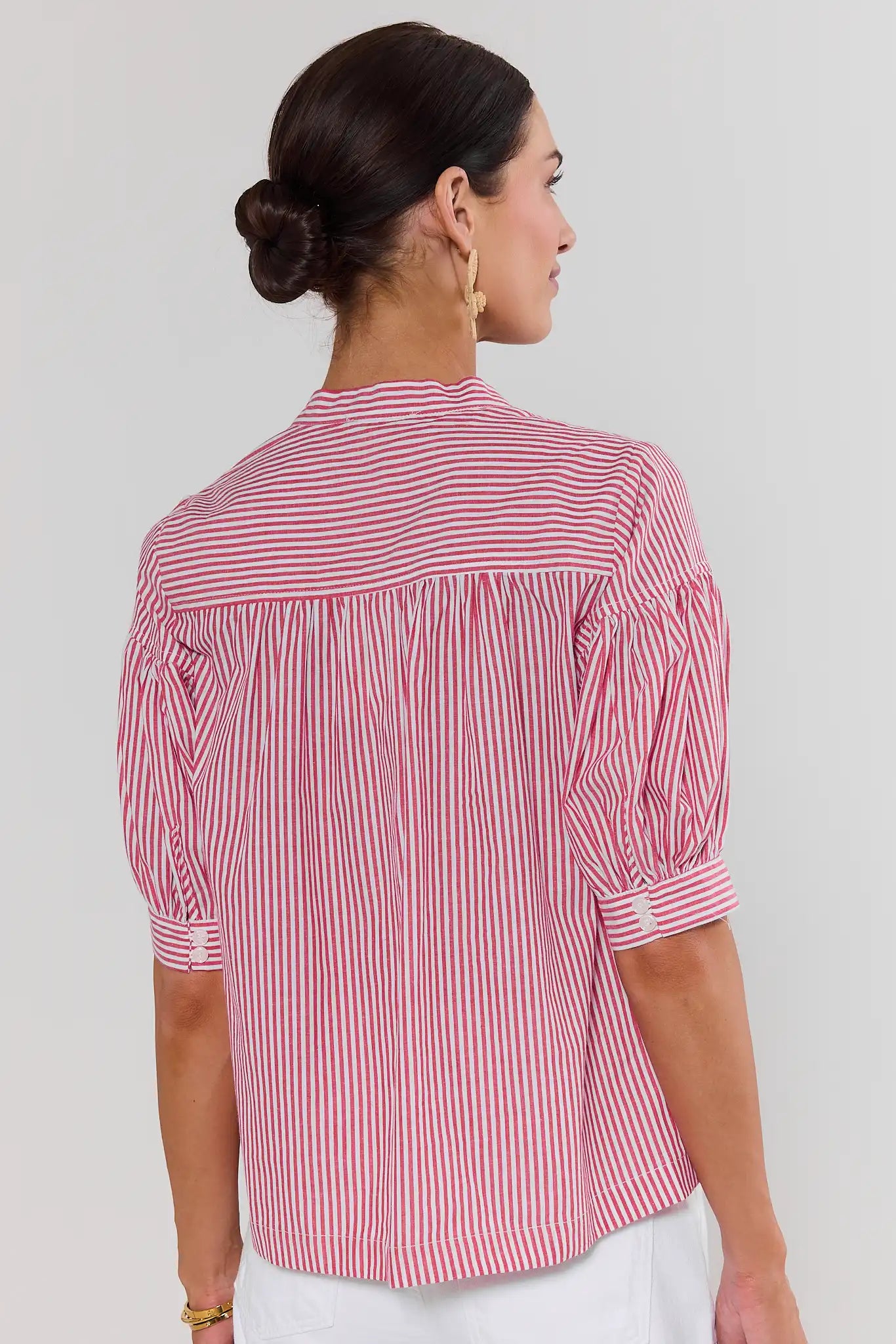 Woman standing wearing a red and white striped shirt against a plain background