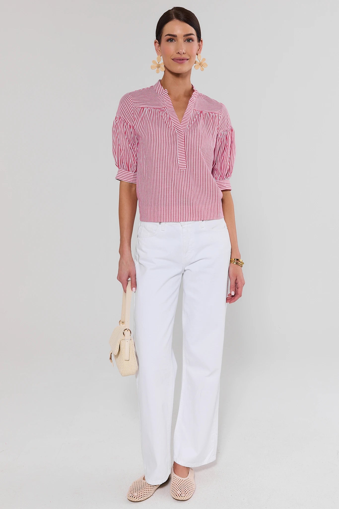 Woman wearing a red and white checkered blouse with white pants on a light gray background