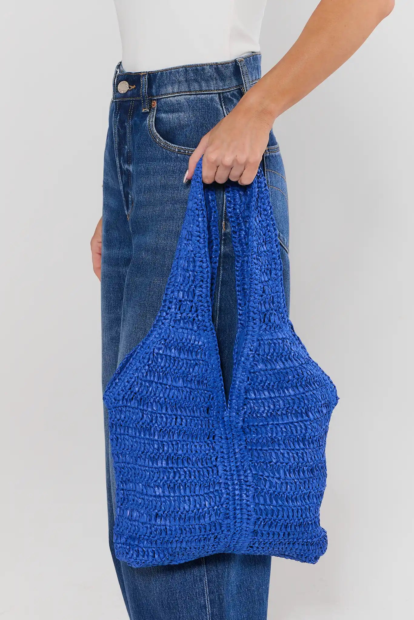 Person holding a blue woven bag against a plain background