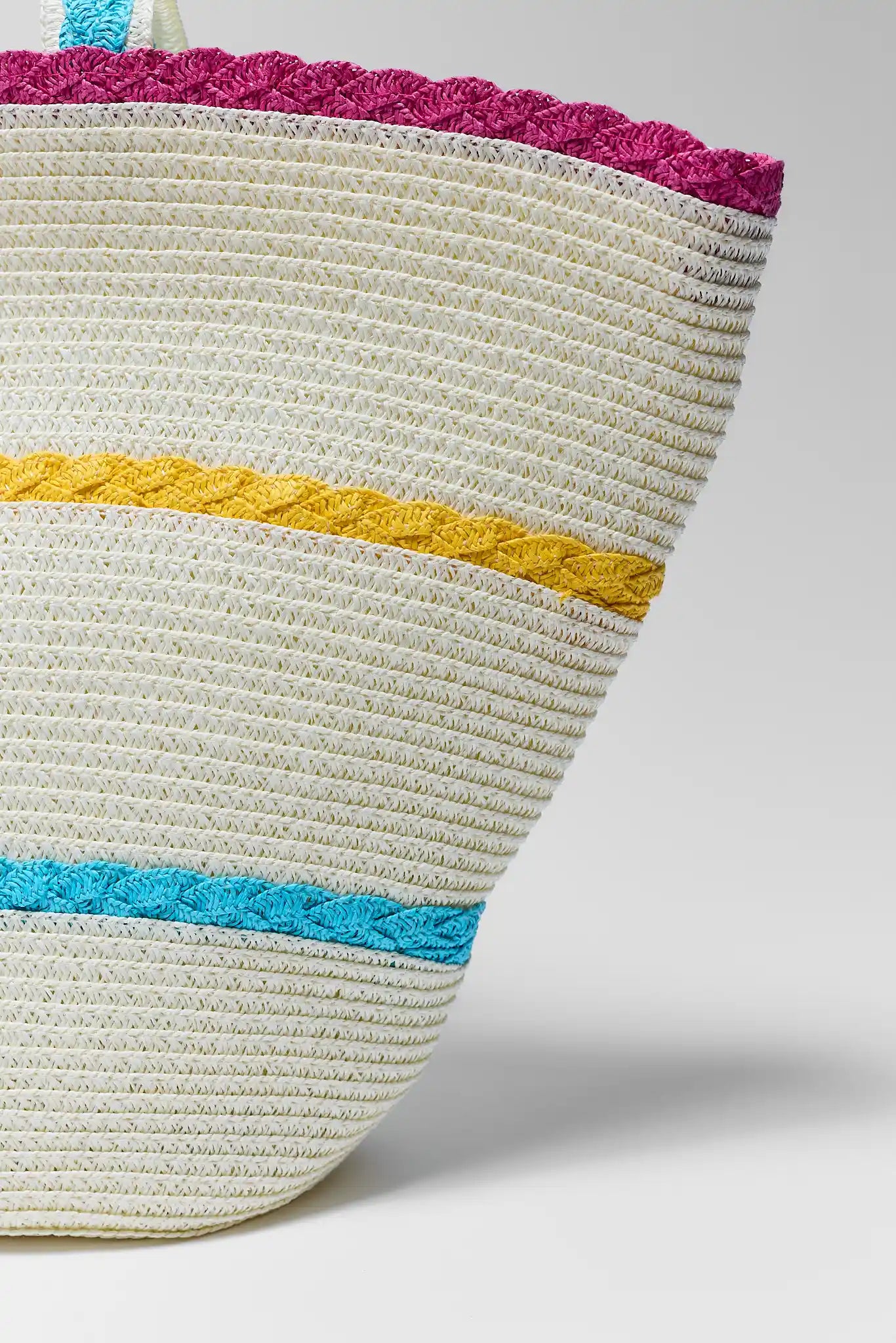 Woven basket with colorful bands on a light gray background close up
