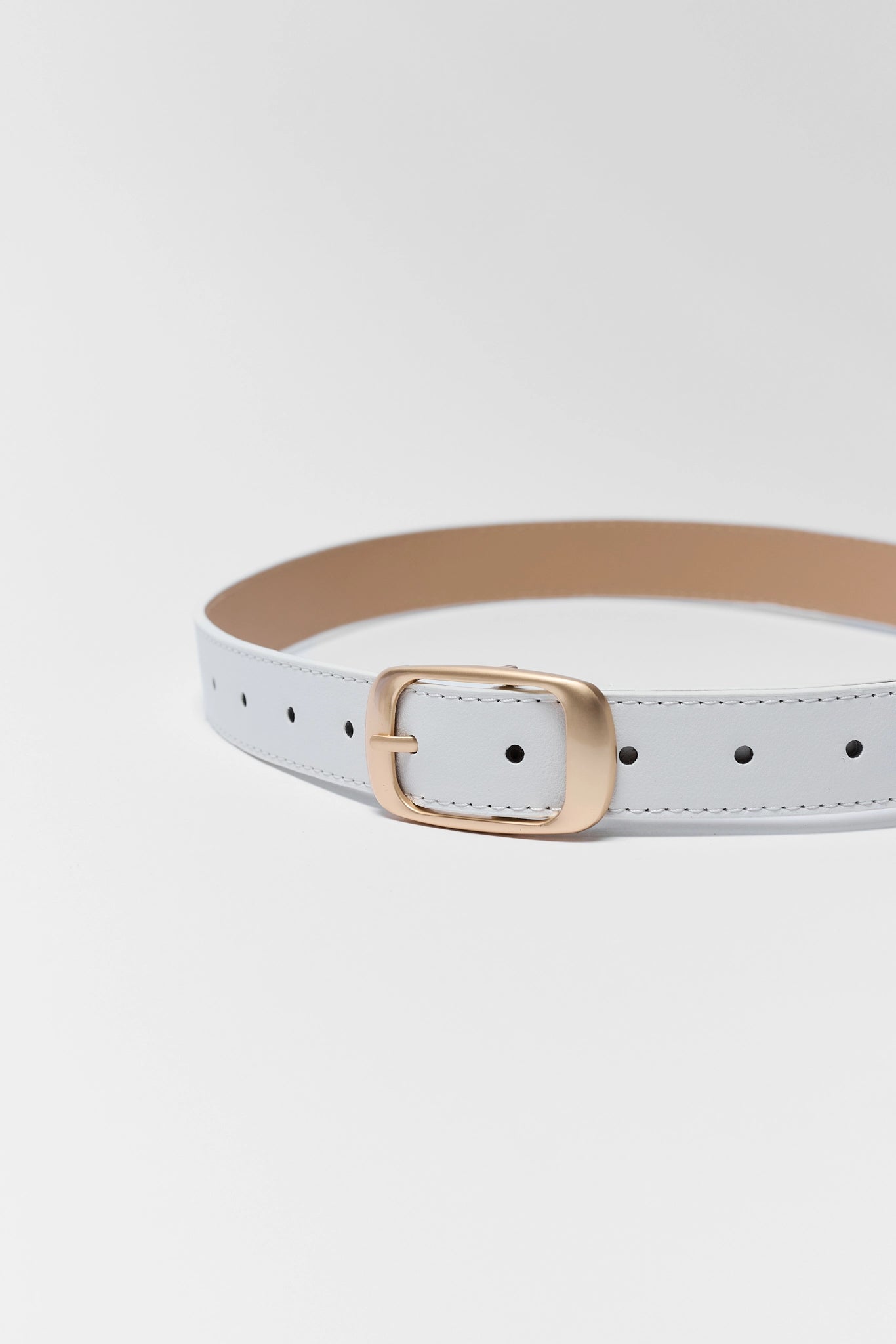 White belt with a gold buckle on a light gray background close up
