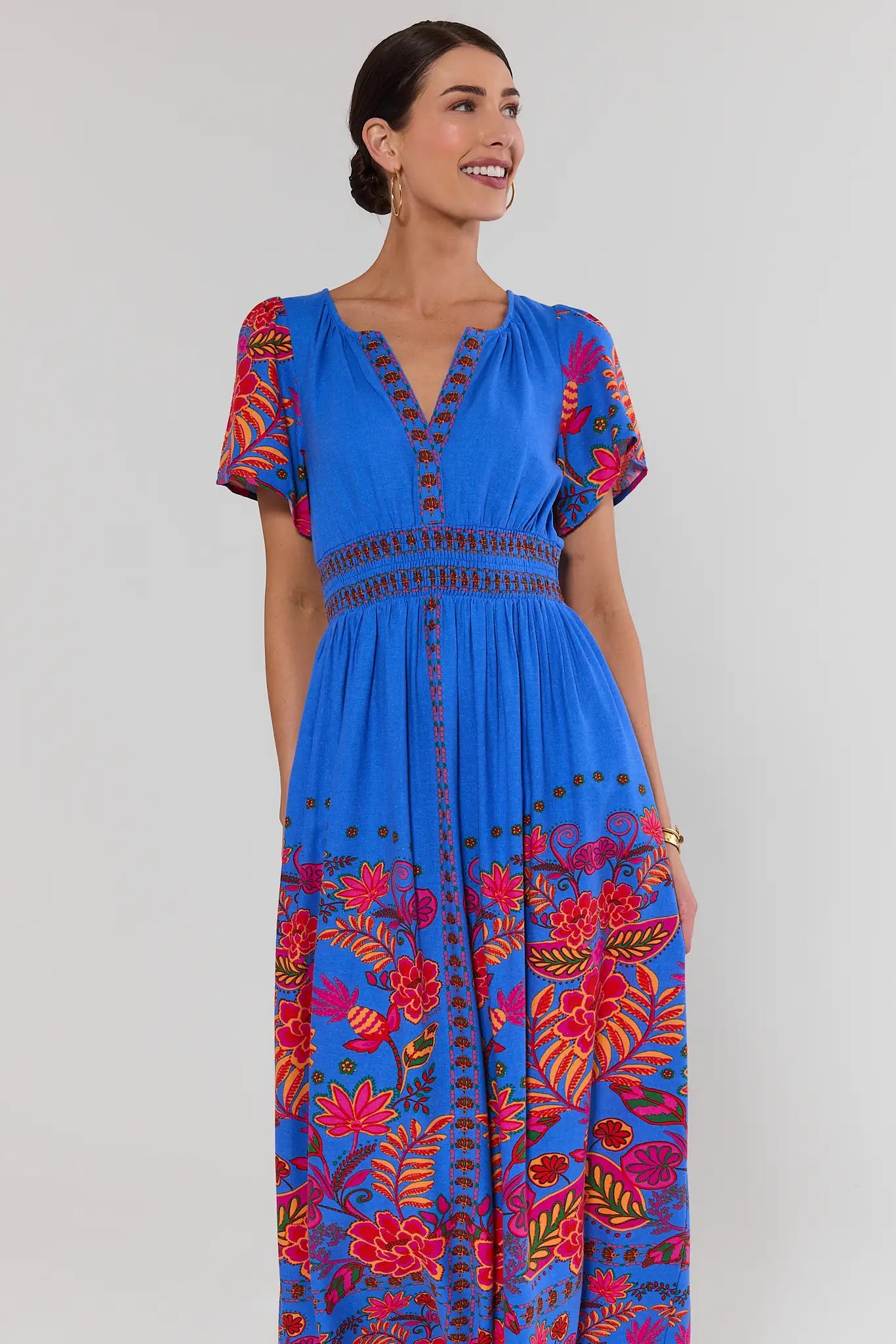 Woman wearing a blue dress with colorful floral patterns on a white background