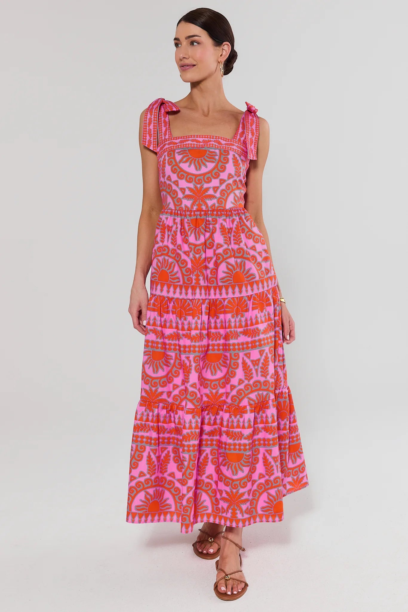 Woman wearing a pink patterned dress on a white background standing