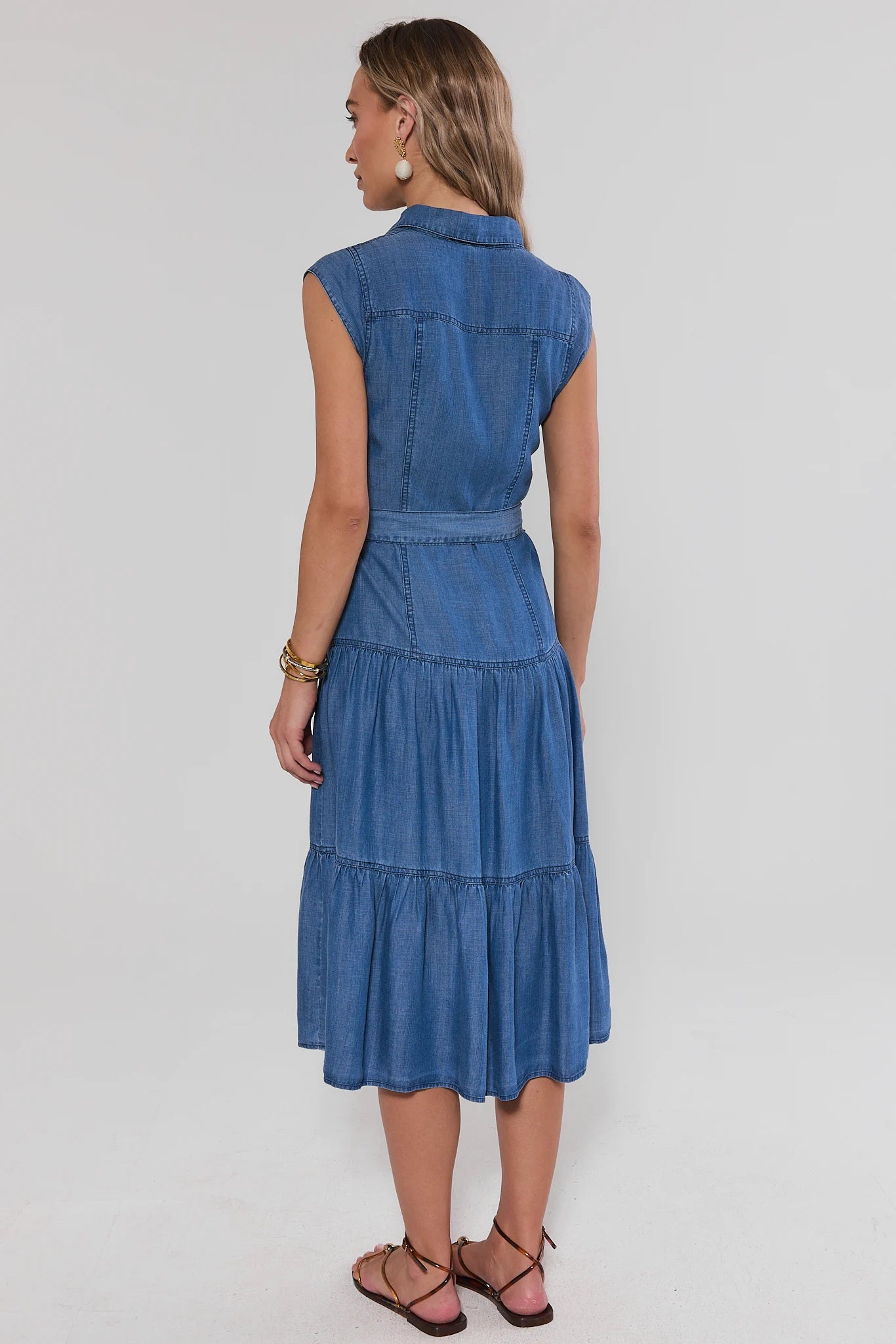 Woman standing wearing a blue denim dress on a white background