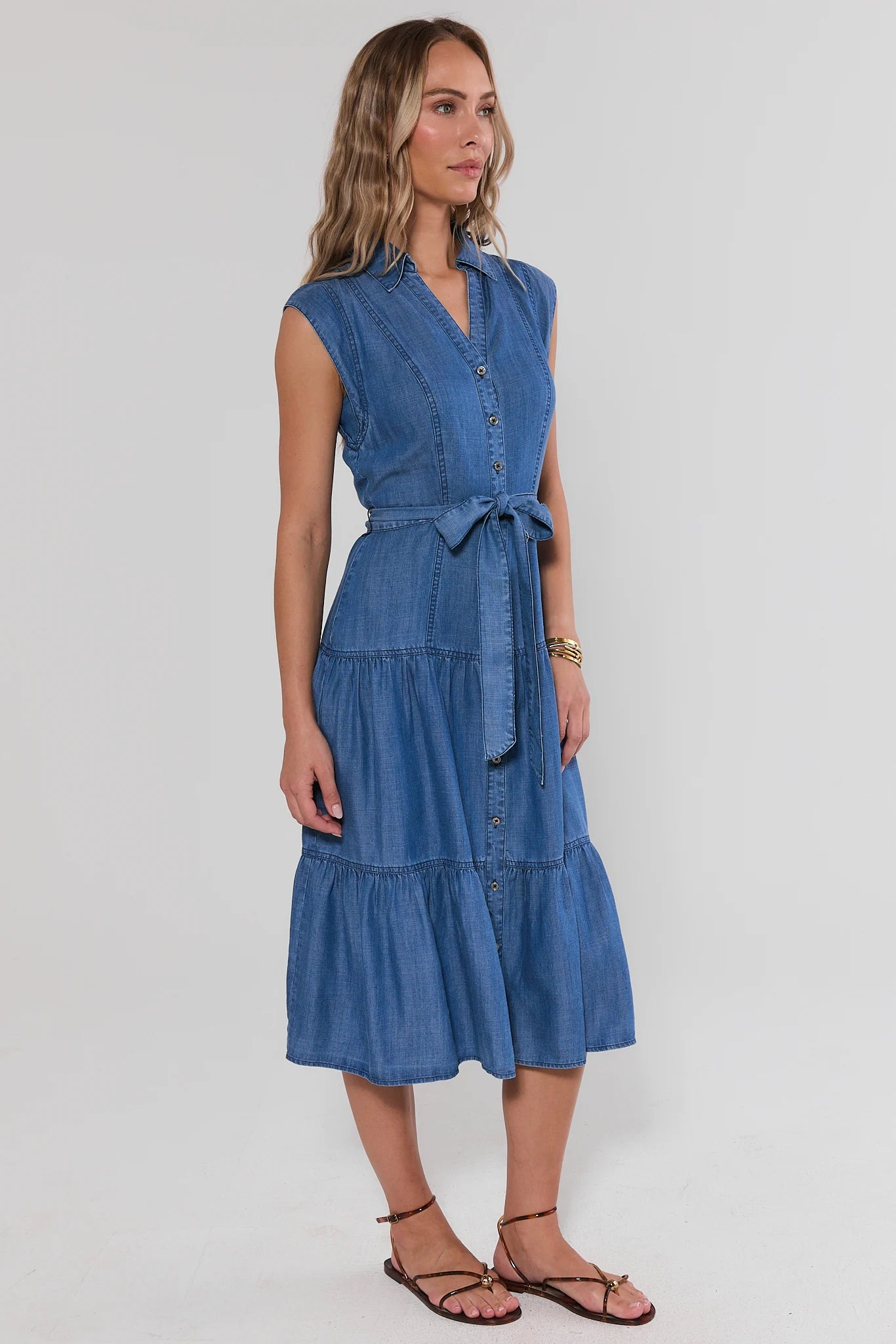 Woman wearing a blue denim dress on a white background side