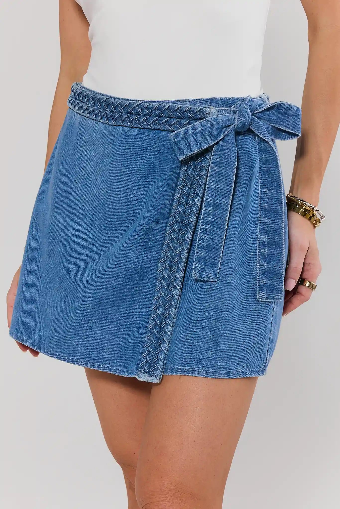 Blue denim skirt with a tie waist on a plain background