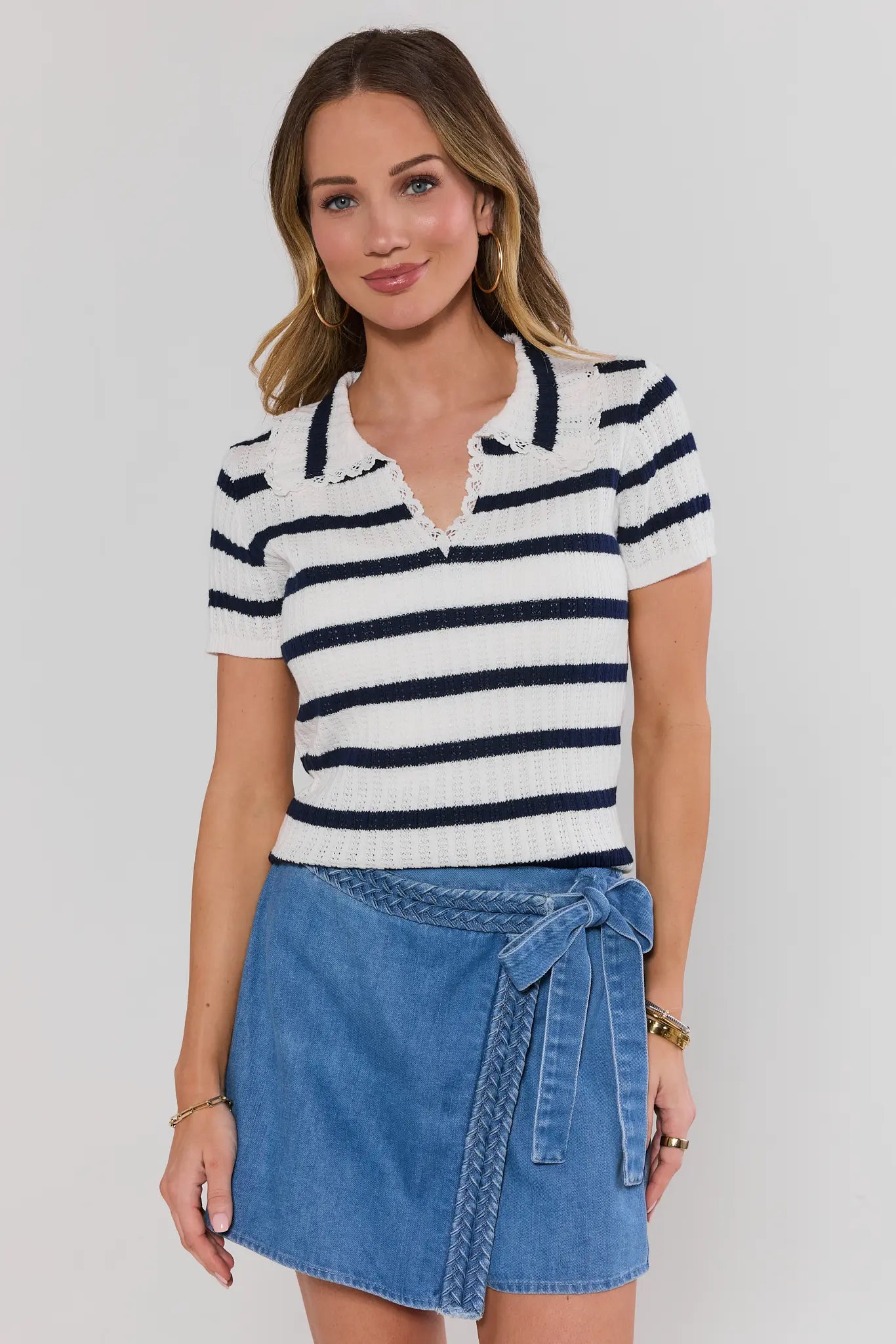 Woman wearing a striped shirt and denim skirt against a plain background