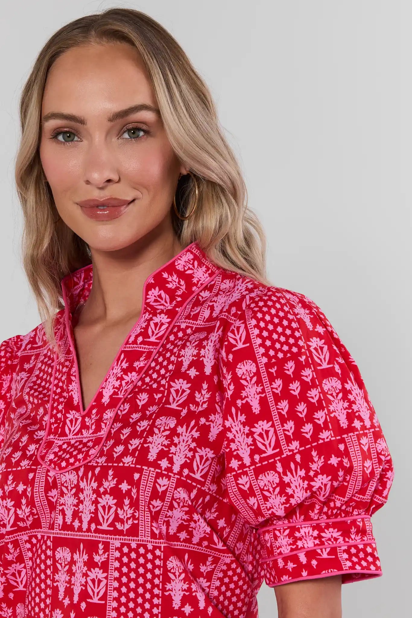 close up Woman wearing a red patterned blouse against a plain background