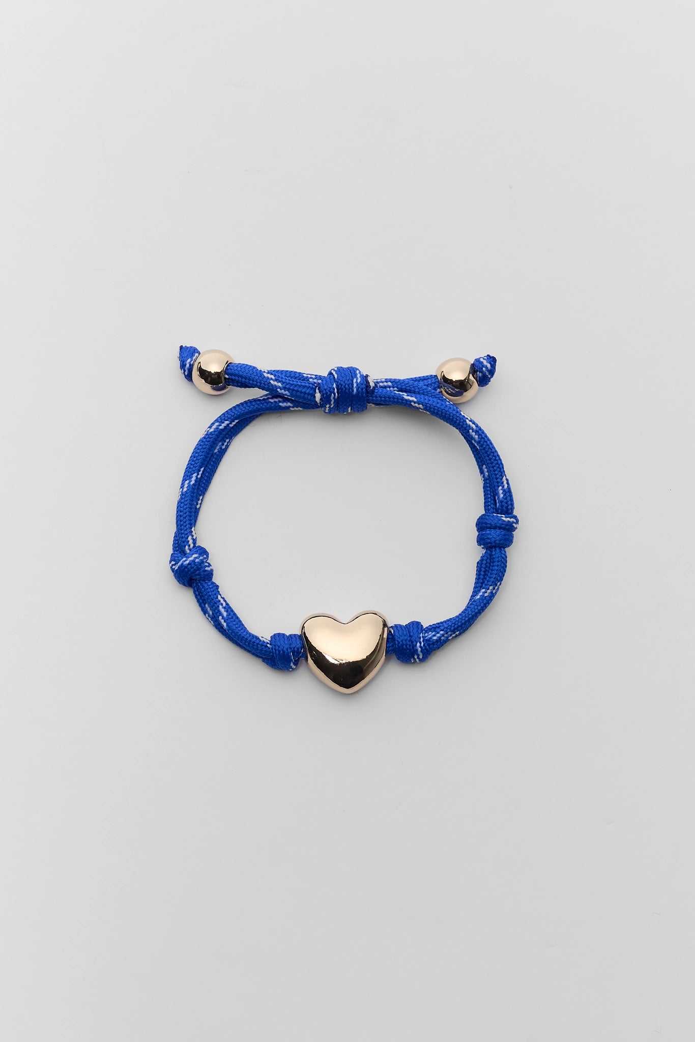 Blue bracelet with a gold heart charm on a light gray background
