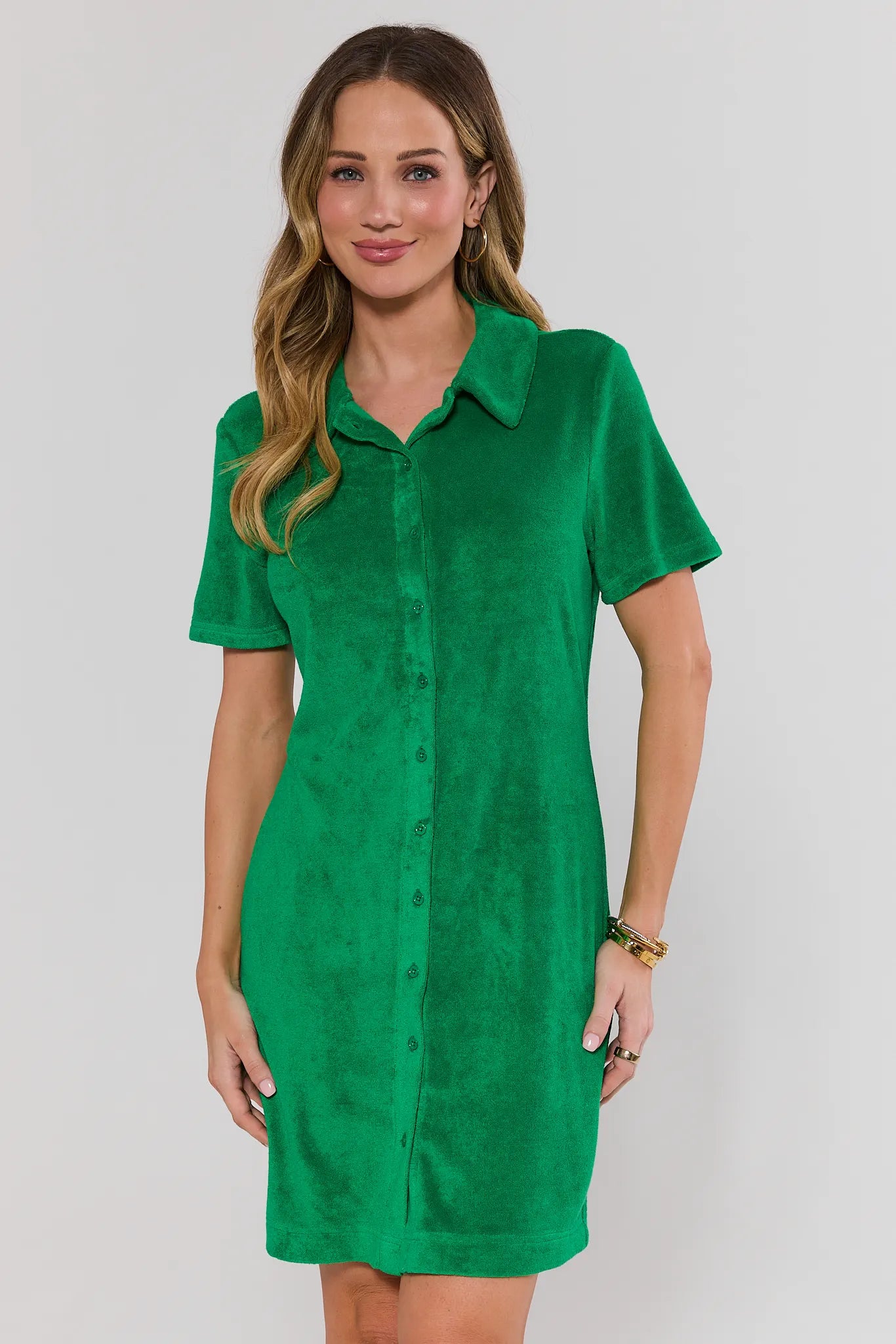 Woman wearing a green dress against a white background standing