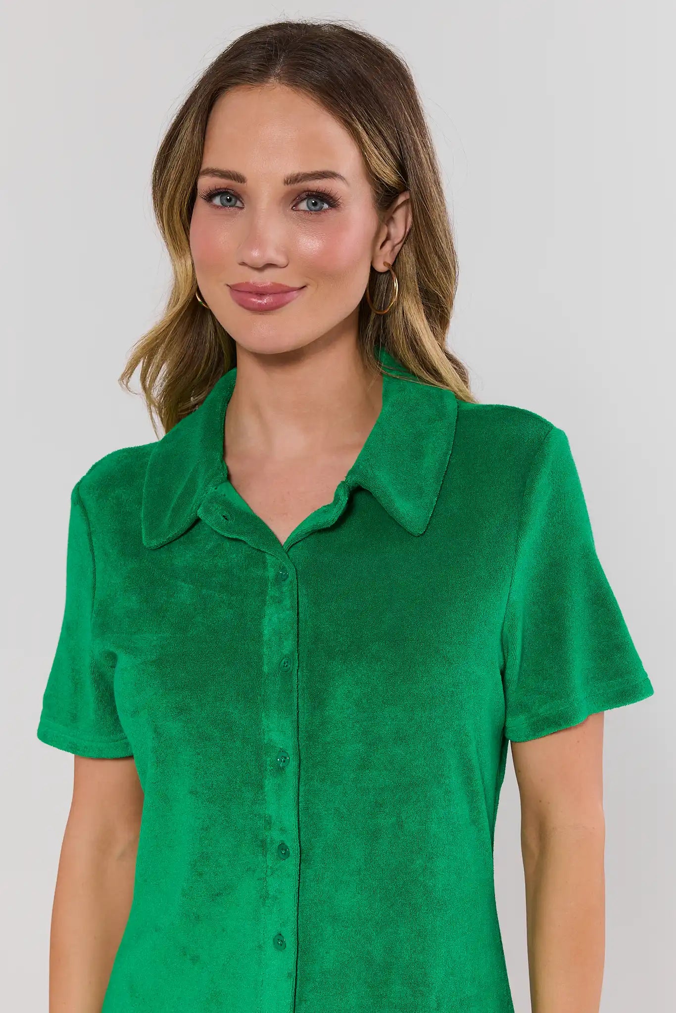 Woman close up wearing a green shirt against a plain background