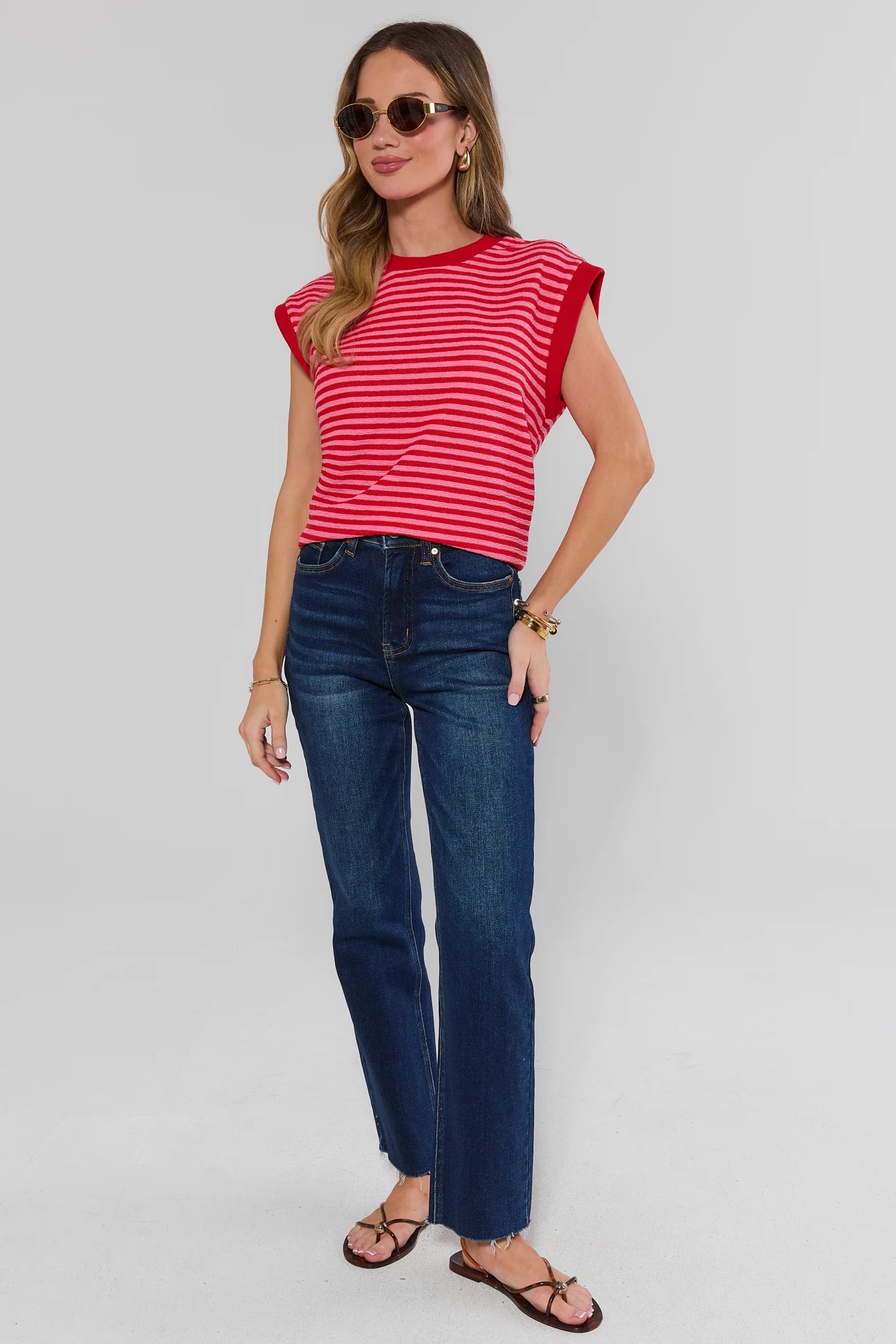 Woman wearing a red and white striped shirt and blue jeans on a gray background