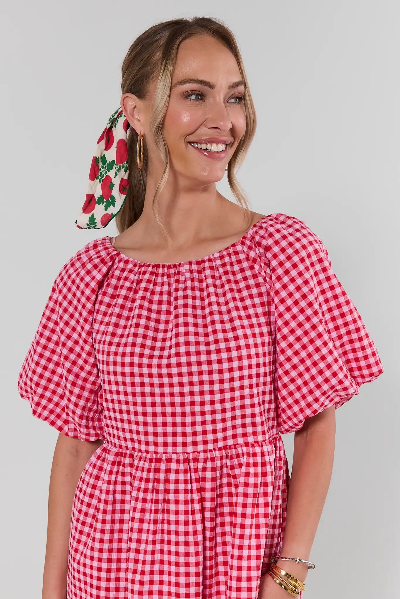 Woman wearing a red and white checkered dress with a plain background close