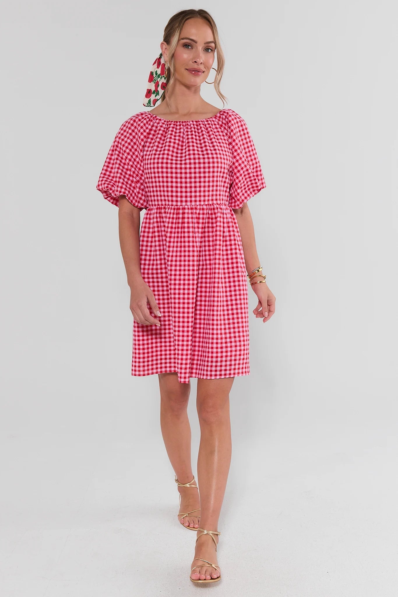 Woman wearing a red and white checkered dress on a light gray background walking