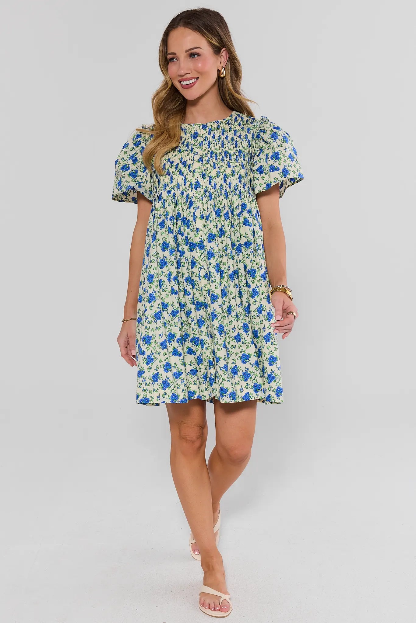 Woman walking wearing a floral dress on a plain background