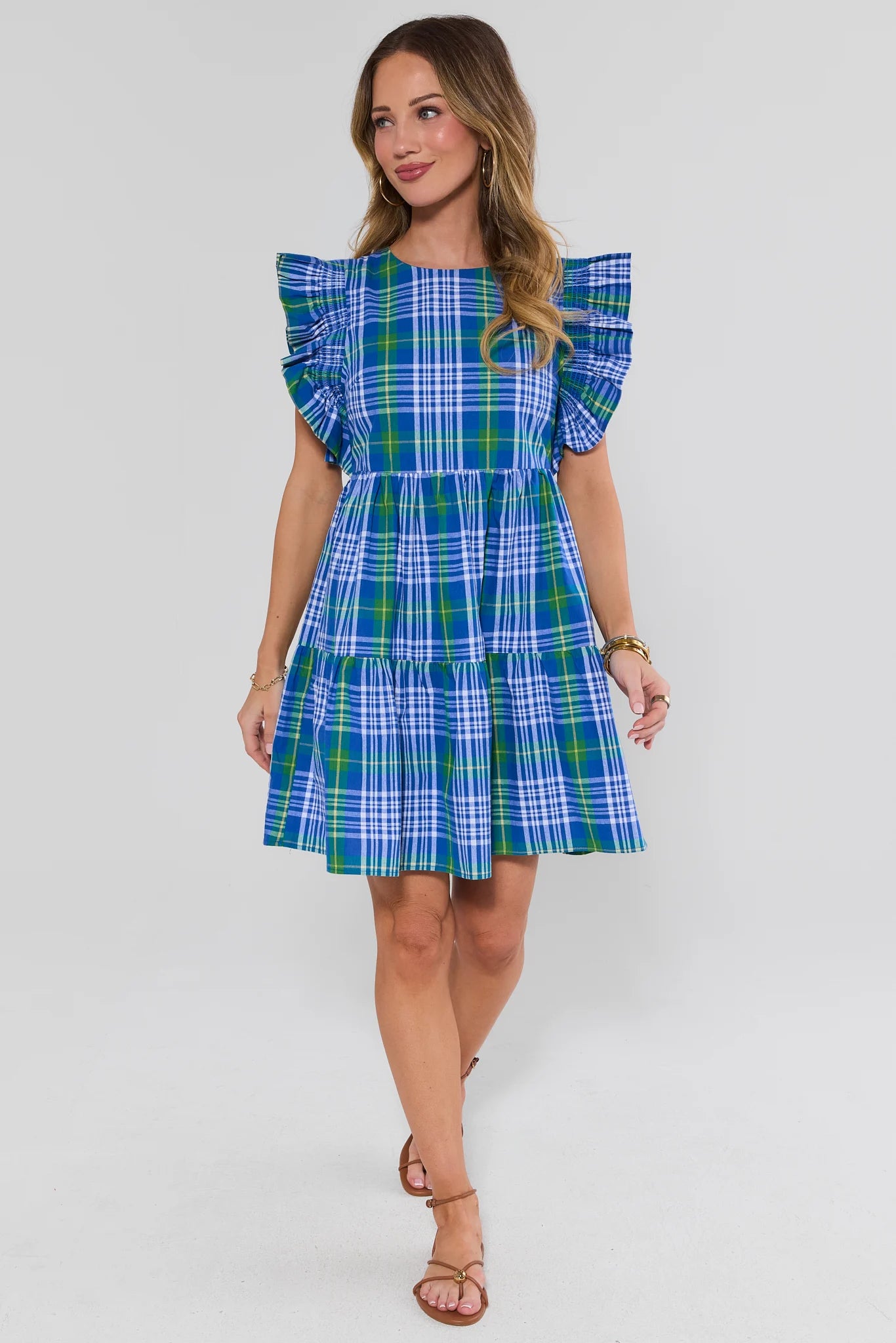 Woman wearing a blue and green plaid dress on a white background standing