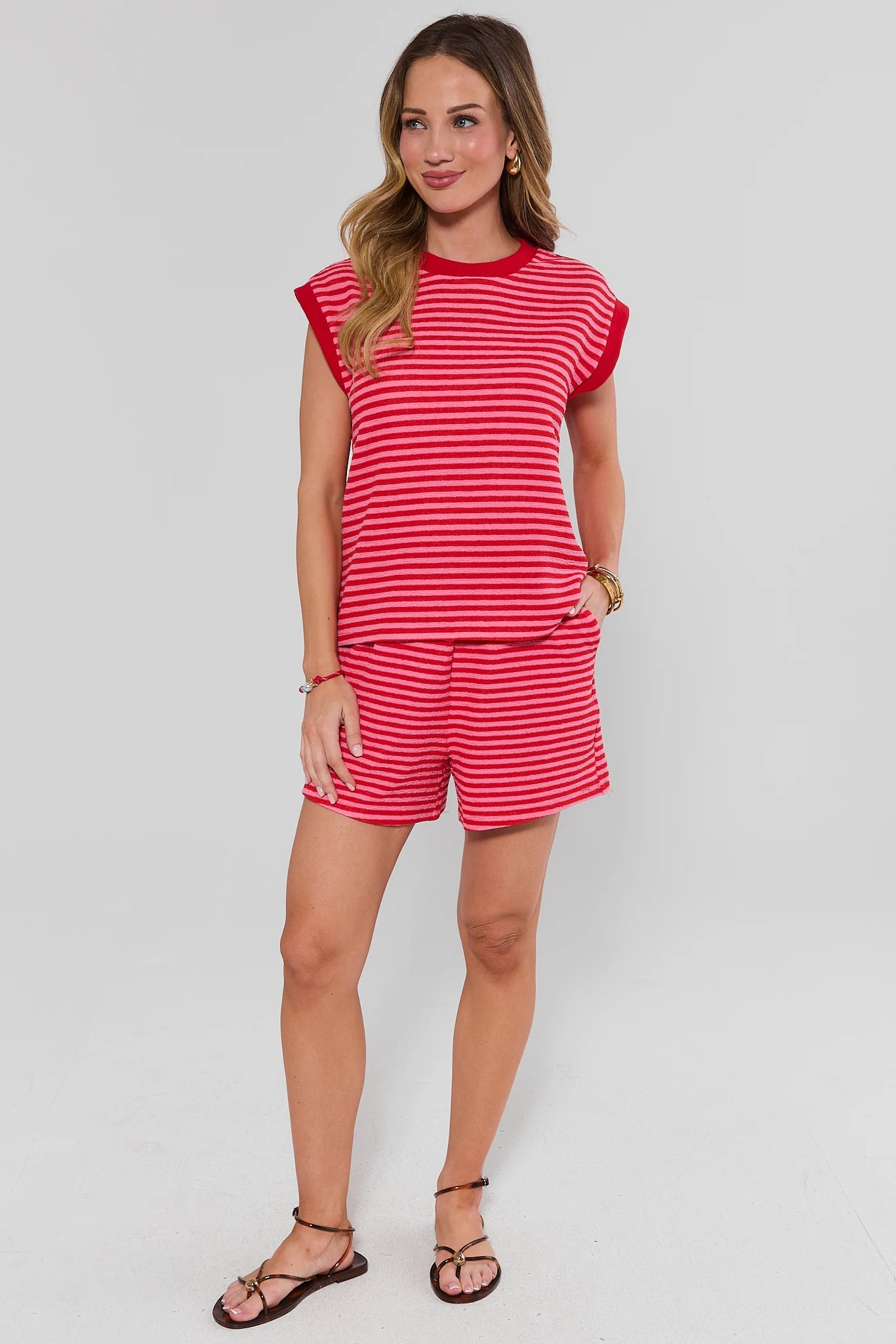 Woman standing wearing a red and white striped outfit on a plain background