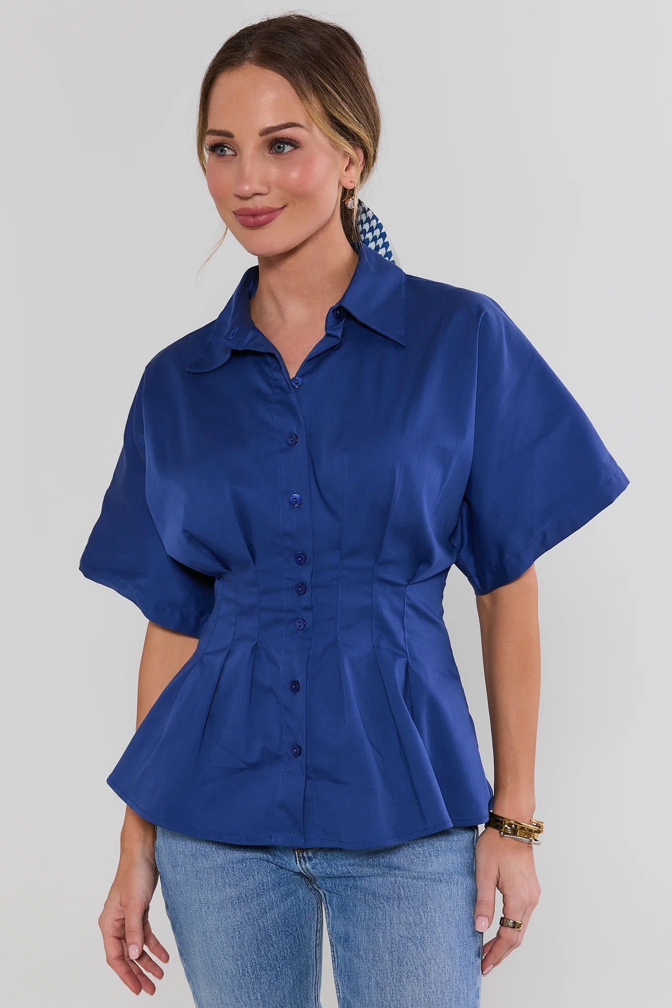 Woman wearing a blue peplum shirt with short sleeves on a plain background