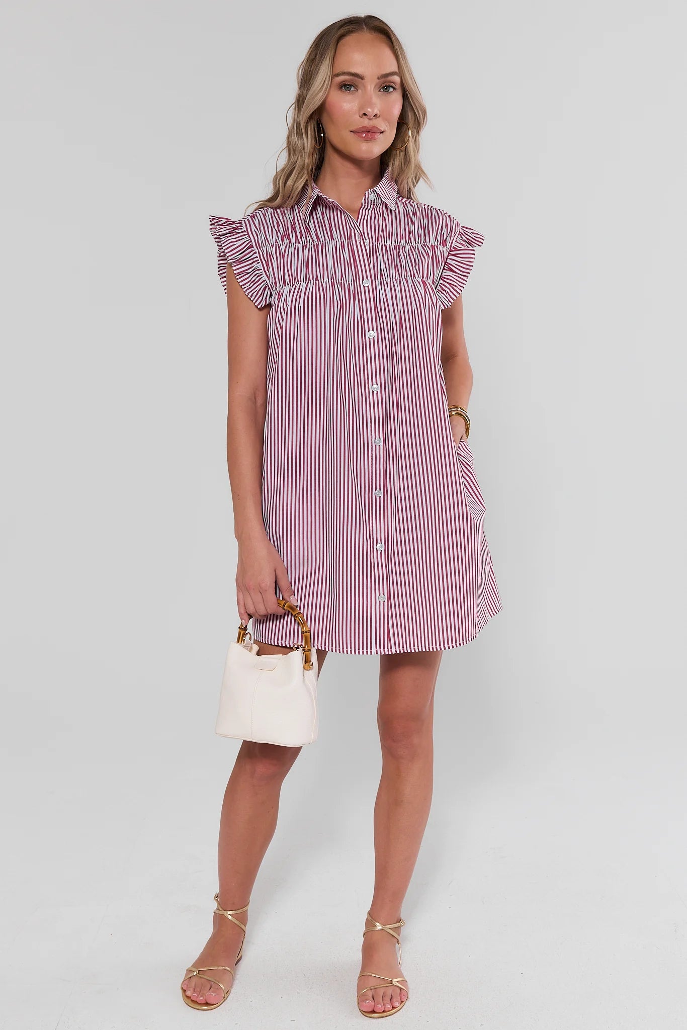 Woman wearing a red and white striped dress on a white background standing