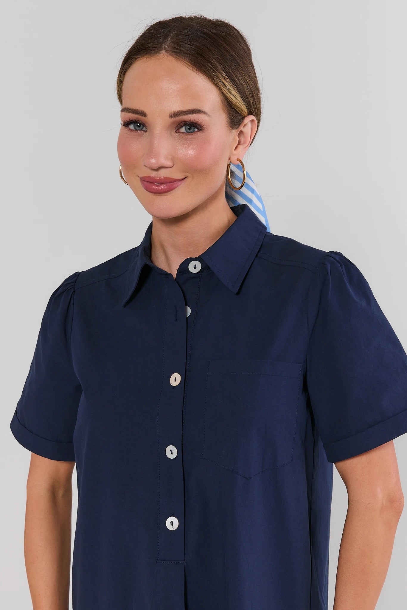 close up Woman wearing a navy blue short-sleeve shirt against a plain background
